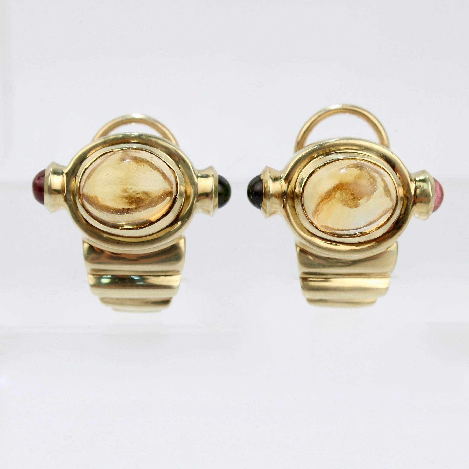 A pair of retro gemstone earrings in 14 karat gold.

At their center, the earrings have a bezel set citrine cabochon that is flanked by a bezel set pink and green tourmaline cabochon on either side.  

Four tapering steps support the