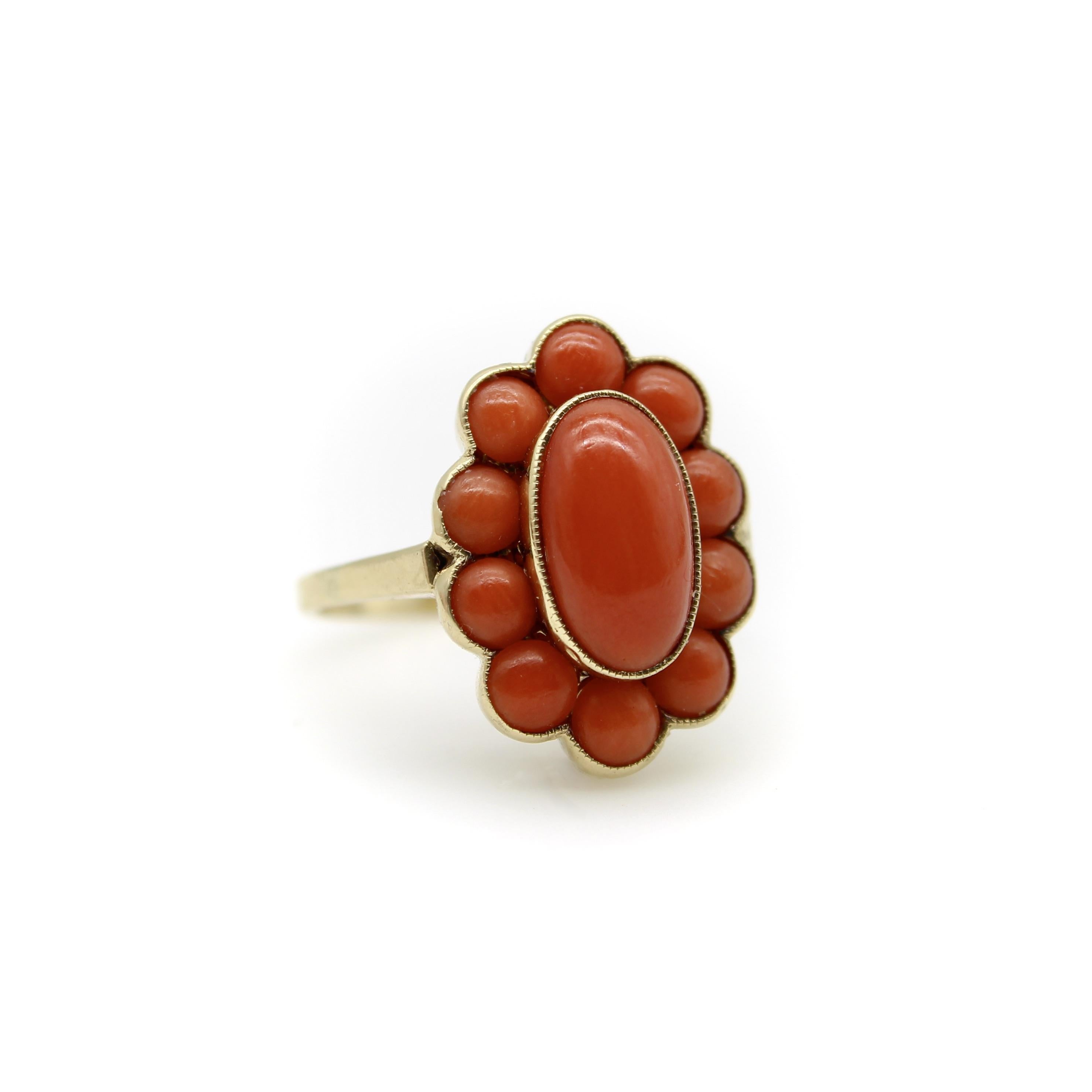 Dieser zarte Ring aus 14-karätigem Gold mit Korallen-Cabochon ist perfekt für den Sommer. Ein ovaler Cabochon ist von einem Kranz kleinerer runder Cabochons umgeben, die eine blumenähnliche Traube bilden. Die Lünette ist mit einer schönen Maserung