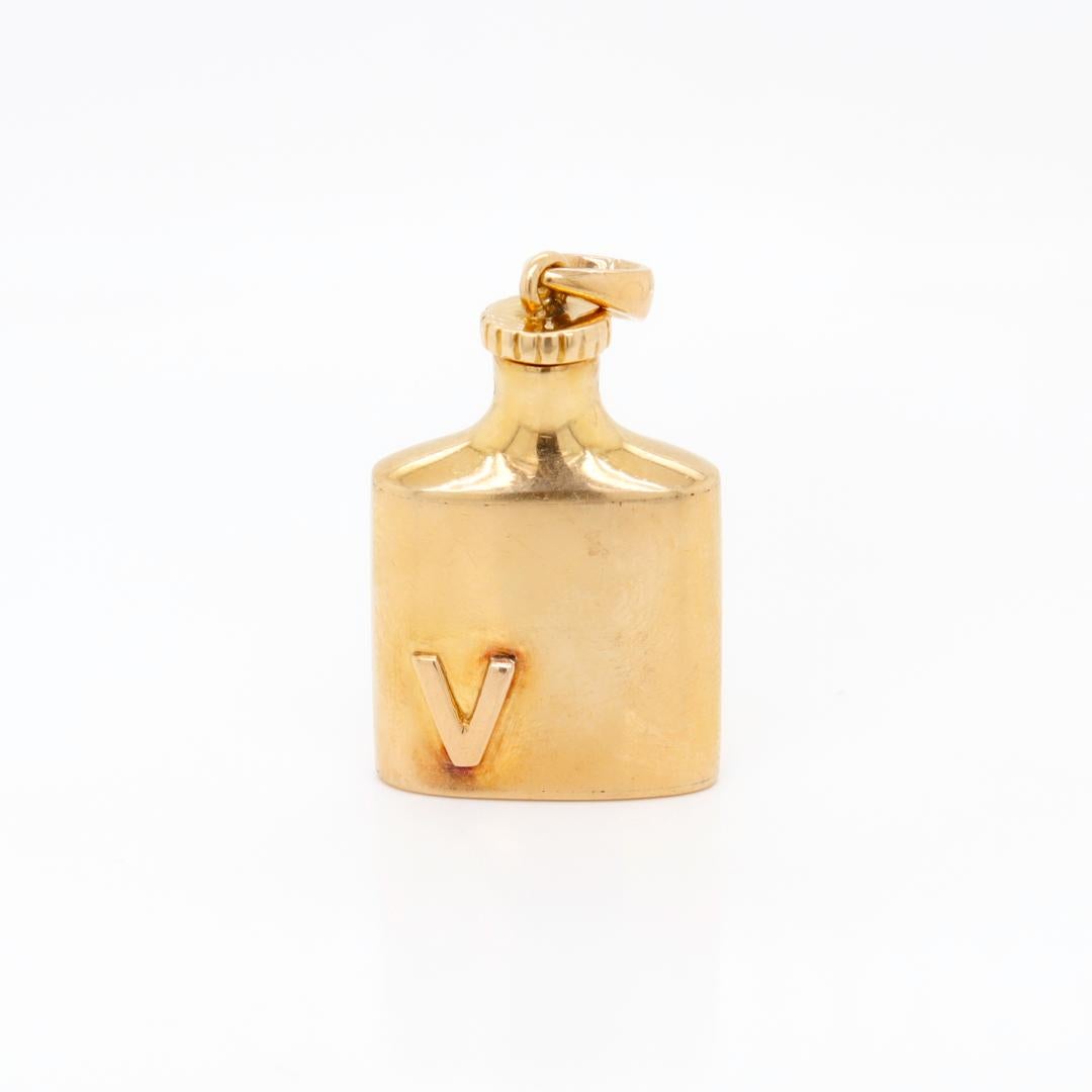 A fine vintage gold charm for a charm bracelet.

In 14k gold 

In the form of a flask with an applied V to one side of the body.

The cap unscrews and has a miniature perfume applicator.

With an integral bail to the cap of the flask.

Simply a