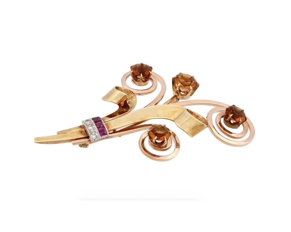 A retro 14K Yellow Gold figural brooch. The brooch is made in a floral design with swirl accents. The brooch is encrusted with diamond cit Citrine stones. The ware is encrusted with Diamonds and Ruby stones. Marked with a standard Gold hallmark, on