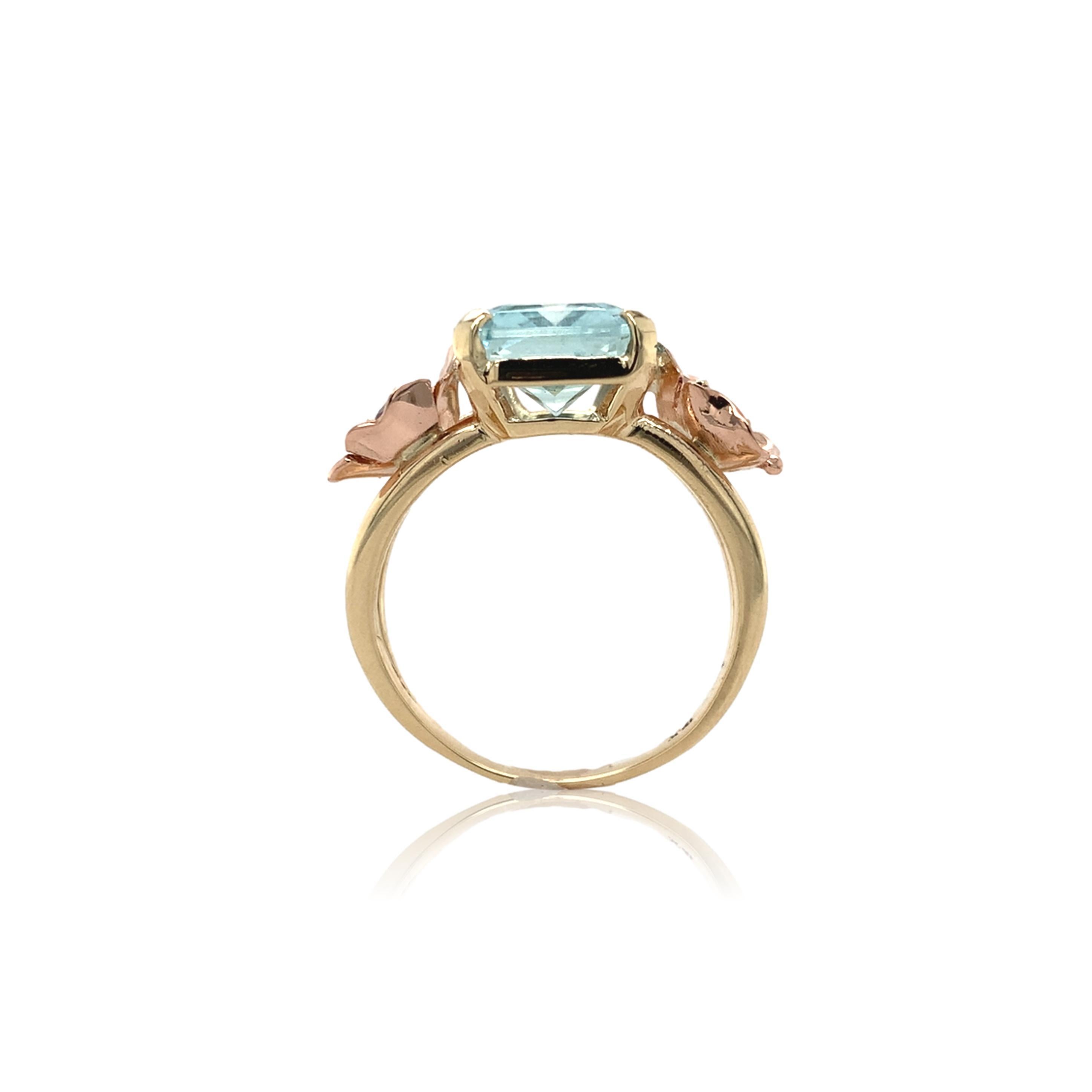 Anillo retro de oro amarillo de 14 quilates con una aguamarina rectangular talla brillante de 4,52 quilates. La aguamarina azul claro mide unos 12,8 mm x 9,4 mm. A ambos lados hay aplicadas flores de oro rosa hechas a mano con rubíes auténticos