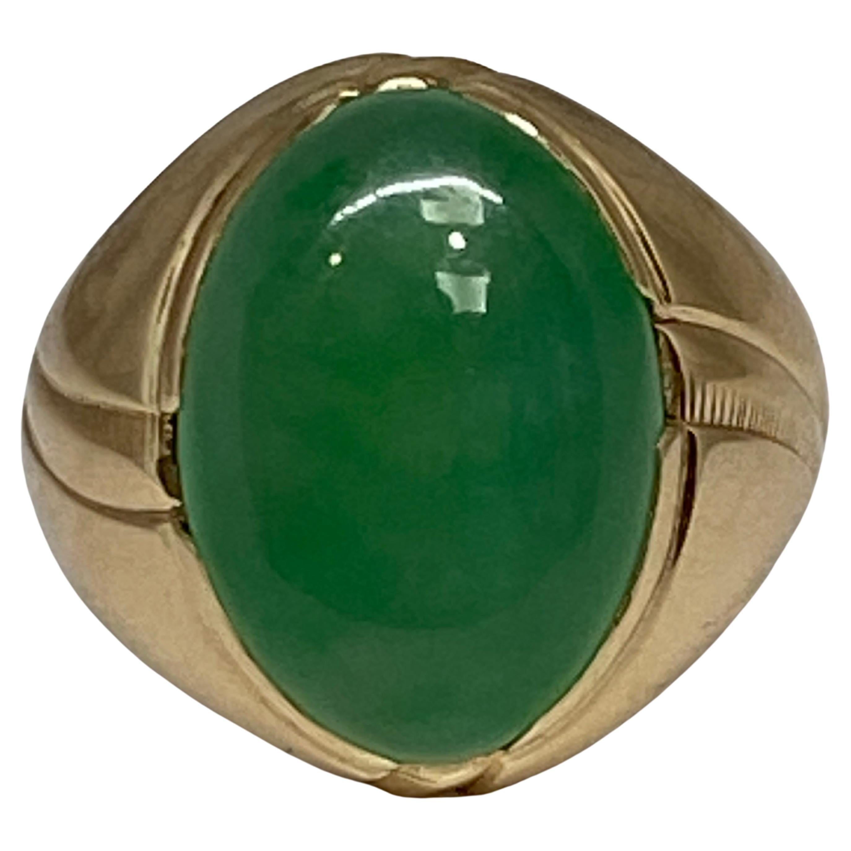 This retro era bold and substantial ring presents a glorious natural green jade cabochon at the center. 

Smooth and glossy, the sizable cabochon shows off its bright vibrant green color vertically atop a gleaming 14K rosy - yellow gold mounting