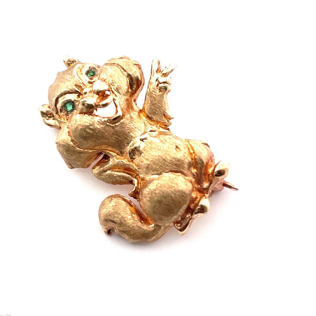 Delightful Chipmunk Brooch, a whimsical masterpiece that captures the essence of woodland charm. 
This captivating brooch, weighing 5.6 grams, is expertly crafted in lustrous 14K yellow gold and features two mesmerizing emeralds, one in each