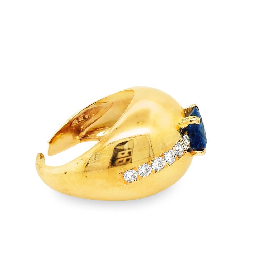 Audace anello a cupola in oro giallo 14K con uno zaffiro blu taglio cuscino incorniciato da dodici diamanti tondi taglio brillante (~0,50 carati in totale). Con un peso di 13 grammi, questo anello retrò combina un design scultoreo con un'eleganza