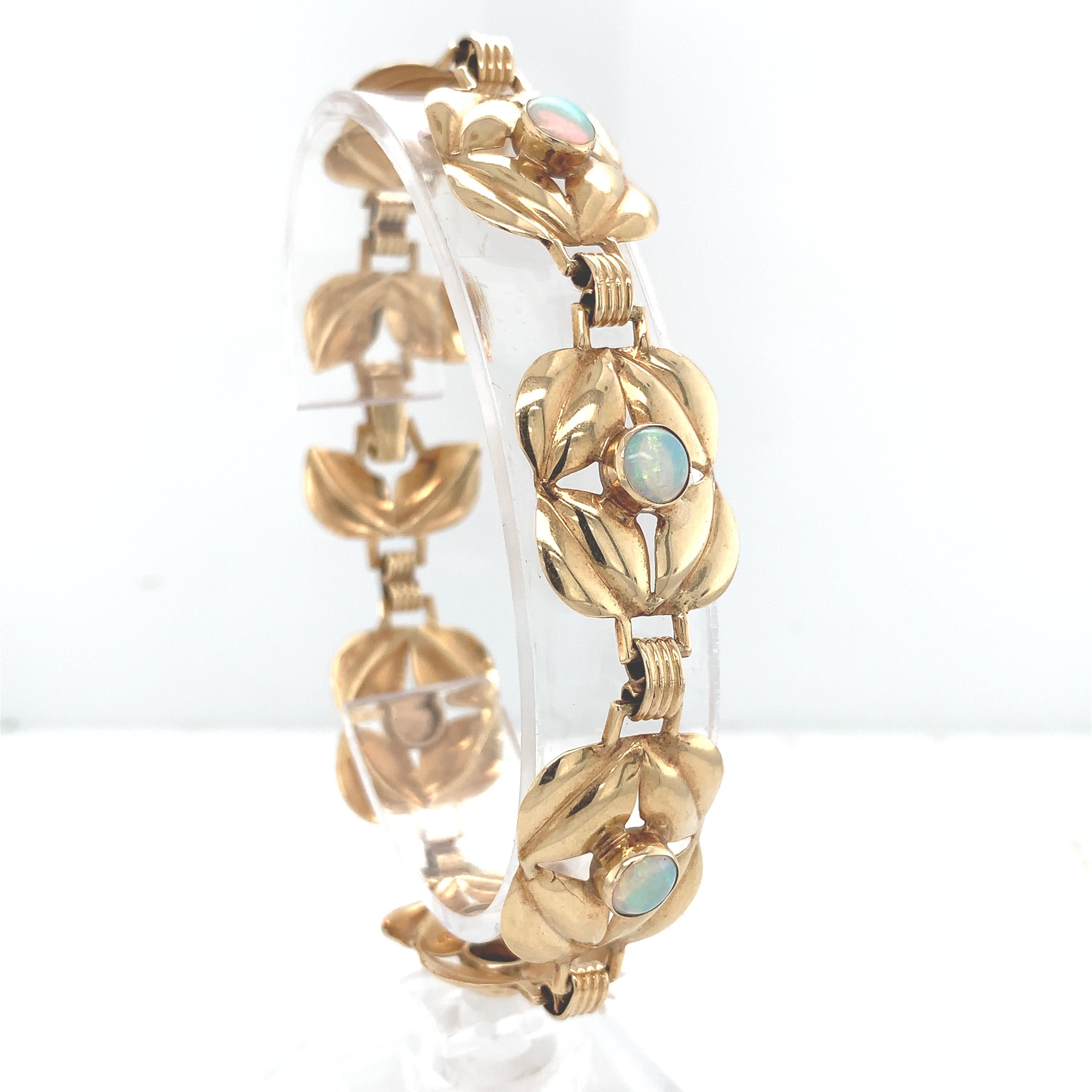 Bracelet rétro en or jaune 14K avec six opales rondes entourées de 4 feuilles stylisées. Les opales ont des jeux de couleurs ardents en bleu-vert et rose et mesurent environ 5 mm. Le bracelet mesure 7,5