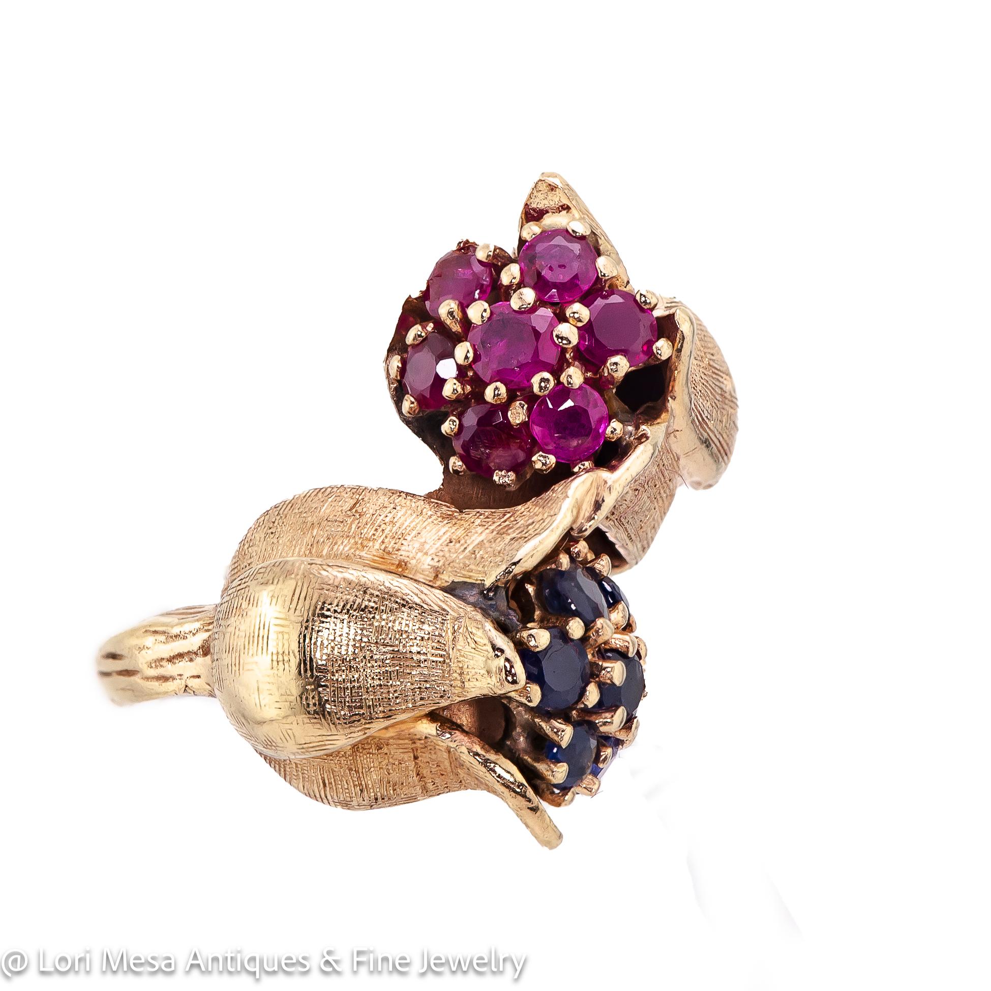 Retro 14kt yellow gold ruby and sapphire floral crossover ring cira 1940 set with seven (7) round rubies and seven (7) round sapphires prong set into a 14kt (stamped) yellow gold floral motif crossover style ring mount.
