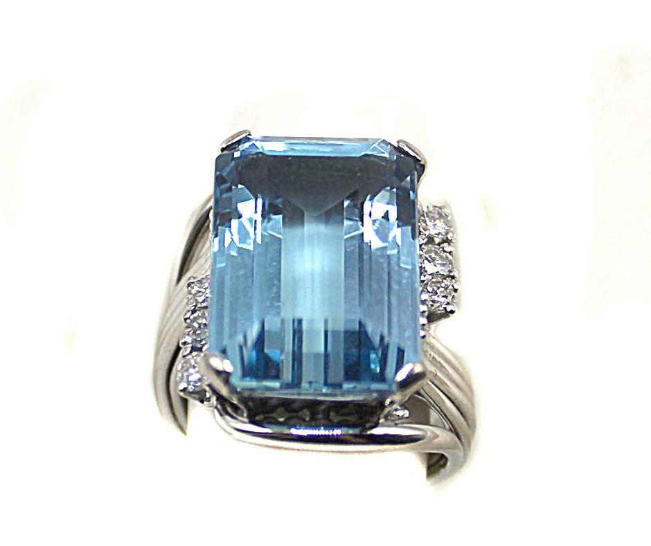 A gorgeous deep sky-blue extremely well saturated Brazilian Aquamarine weighing 15.30 carats is the center piece of this chic and bold platinum Retro ring from ca. 1950. The amazingly well cut rectangular emerald-cut gemstone displays a wonderful