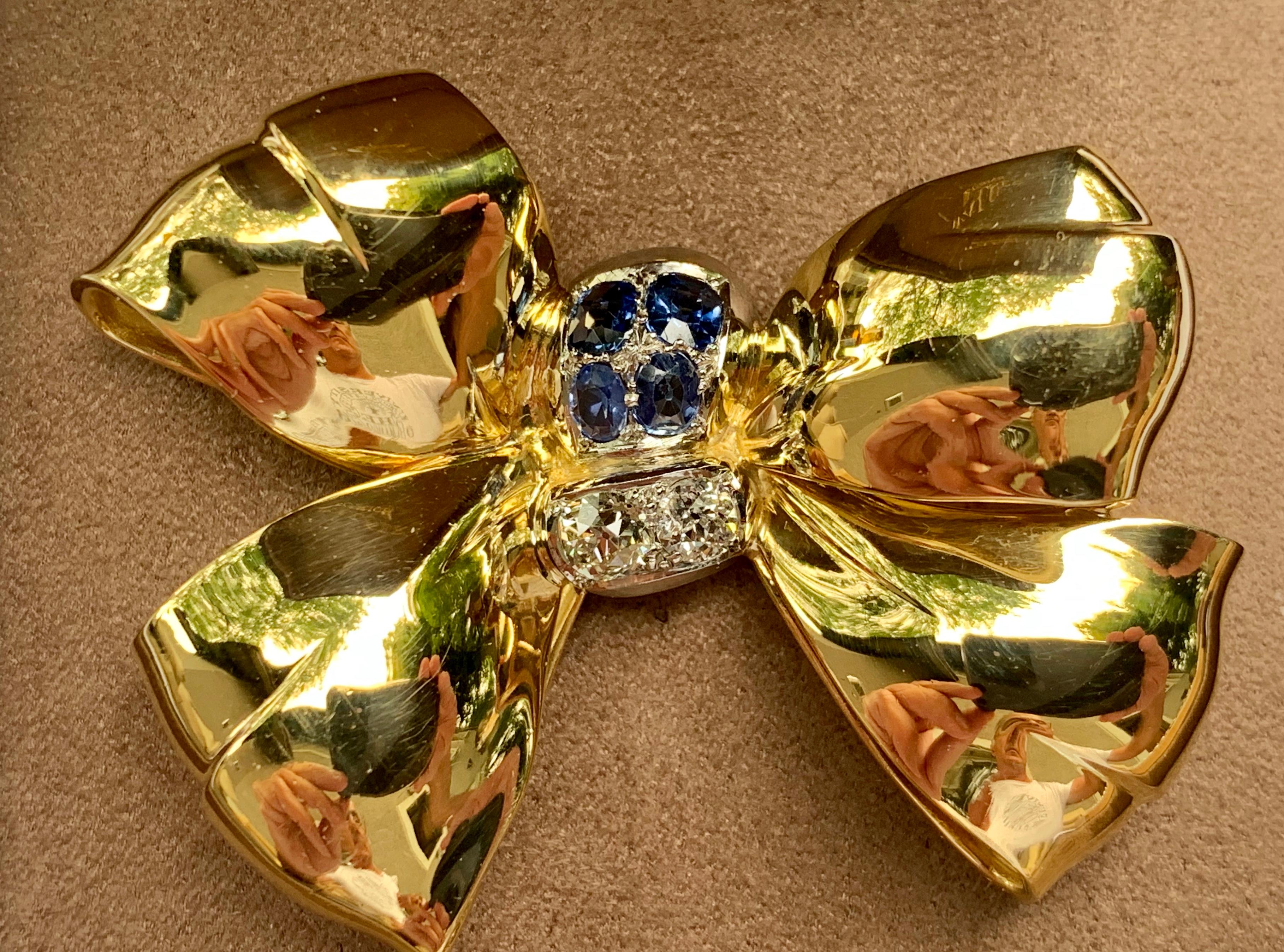Elegant 18 K yellow and white Gold Vintage bow brooch with natural Sapphires and Diamonds. The brooch is  quintessentially Retro in design. 4 Ceylon Sapphires weighing approximately 1 ct and 2 old European cut Diamonds weighing approximately 0.90