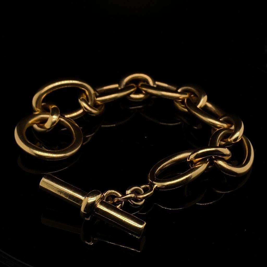 A retro chunky bangle set in 18 karat yellow gold, circa 1950.

This bold and heavy bracelet is comprised of curved polished cable links with an unusual and fun extra large T-bar security fastening clasp which loops through the rounded end
