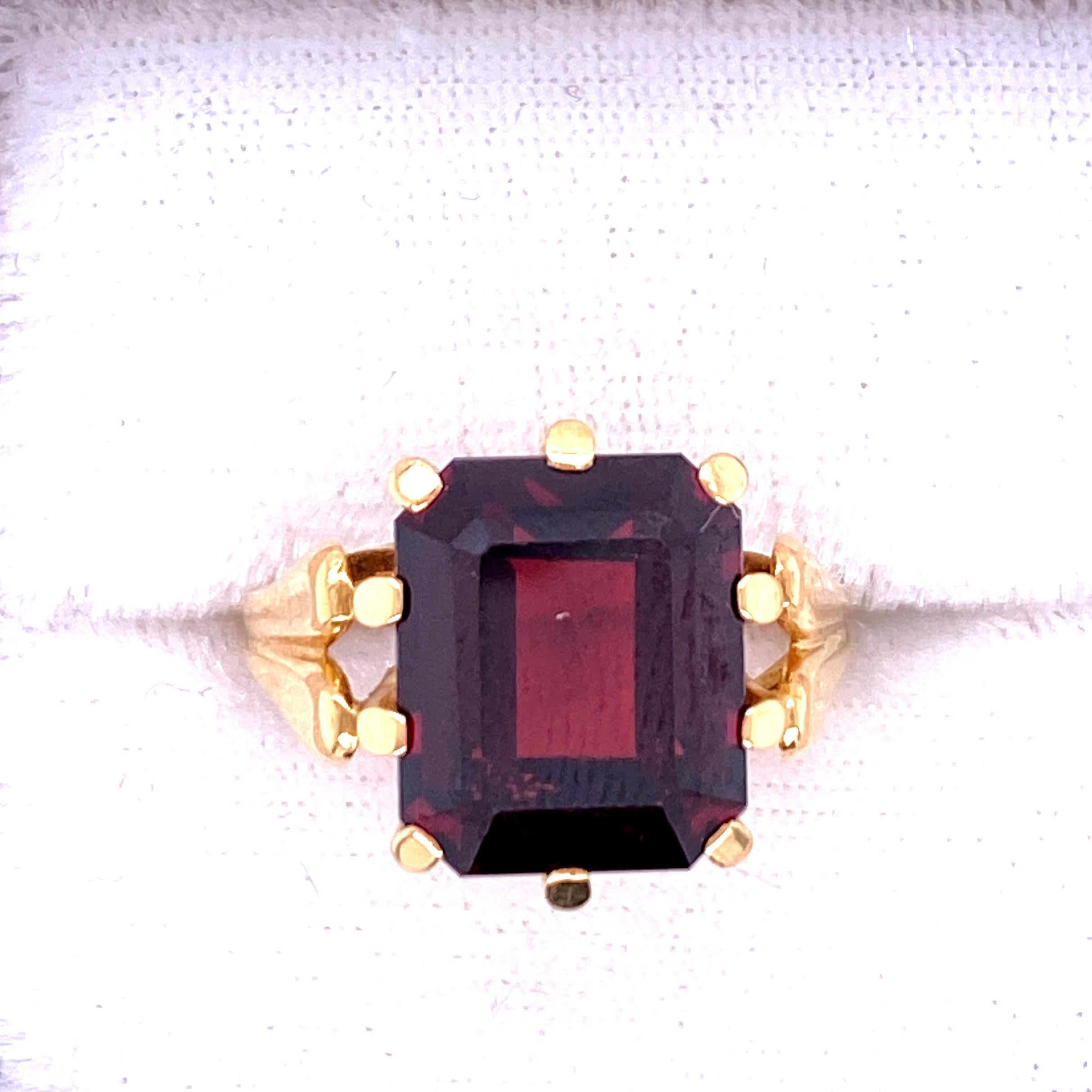 One 18 karat yellow gold (stamped 750 HFW) ring prong set with one 12 x 10mm emerald cut garnet.  The shank measures 6.6mm near the top of the ring and tapers to 1.5mm at the base.  The ring is a finger size 5.25.  Circa 1960s. 