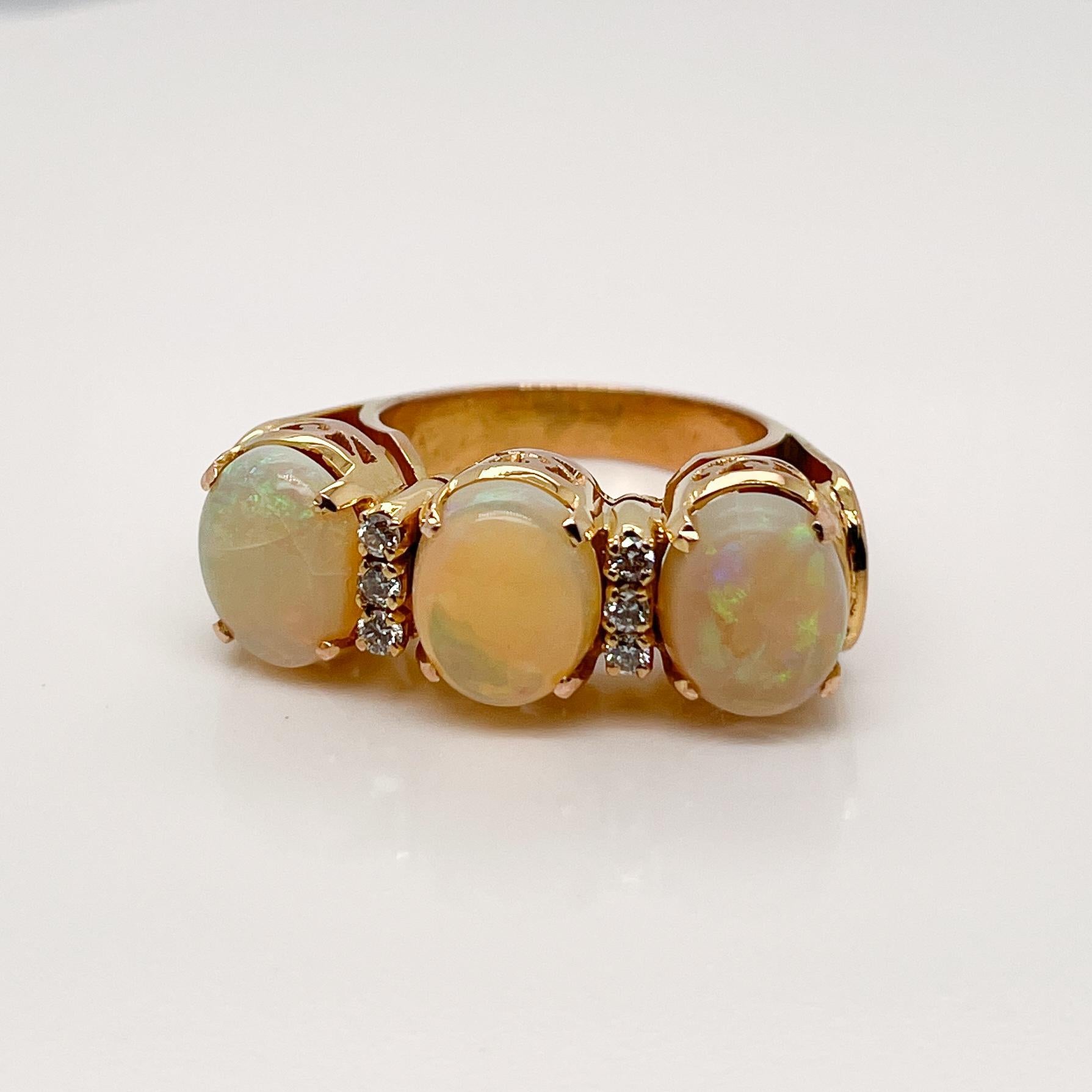 A very fine opal and gold cocktail ring.

With 3 prong-set smooth oval opal cabochons offset by 2 rows with 3 small round brilliant diamonds each. 

In 18k gold.

Simply a wonderful Retro cocktail ring with lovely opals and sparkling
