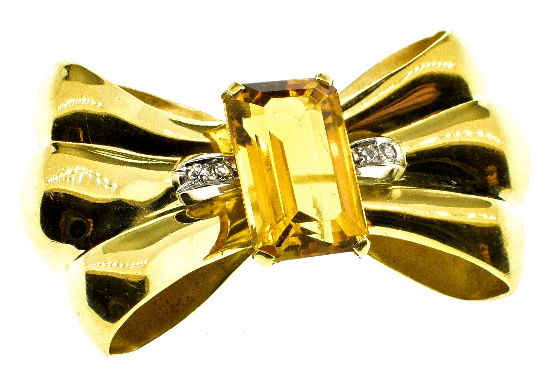 Retro 18K gold brooch centering an emerald cut natural bright citrine weighing approximately 10 cts. and accented on both sides with small white diamonds.  This three dimensional piece is 1.75 inches long and weighing 16.27 grams.  Circa 1950 in