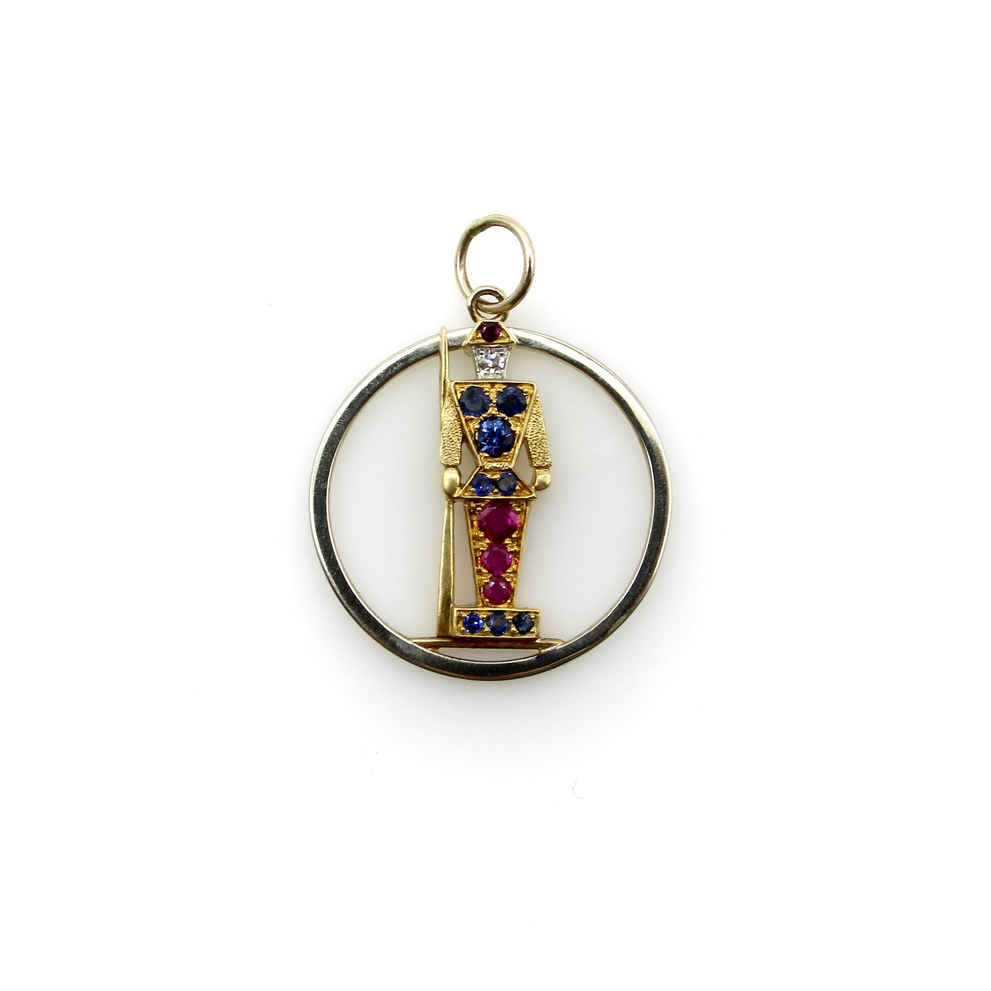 This 18k gold soldier-like guard stands at attention. His body is simplified into geometric shapes and detailed with rubies and sapphires of various sizes, all bead set. His face consists of a diamond, which is outlined in white gold to create
