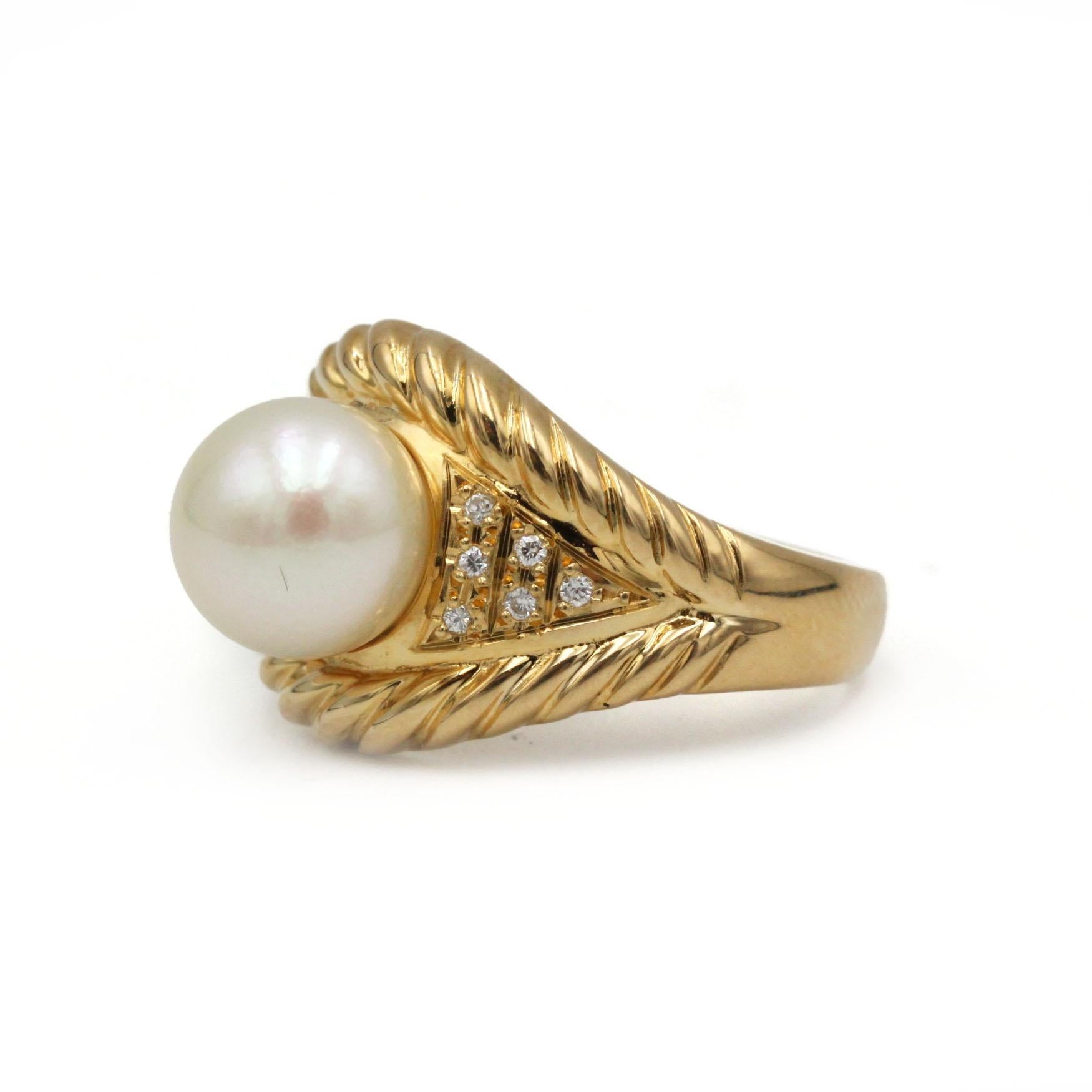 Entra in un mondo di raffinato glamour con questo sorprendente anello da cocktail retrò, squisitamente realizzato in ricco oro giallo 18 carati. Al centro, una perla rotonda e lucente brilla con un'iridescenza color crema, splendidamente incastonata