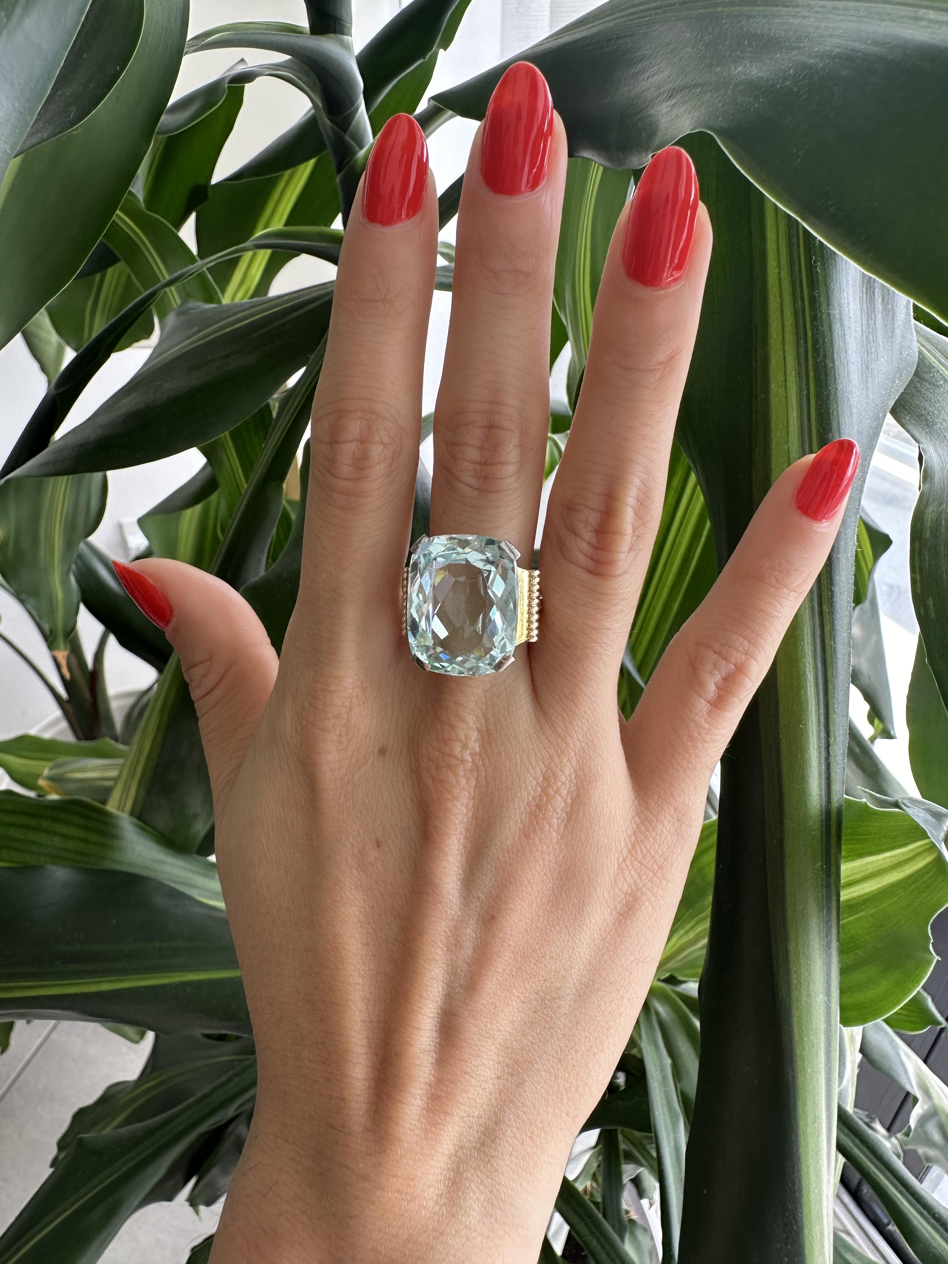 Prepare to be captivated by the timeless beauty of this Retro 18k yellow Gold Ring, featuring a magnificent center Aquamarine weighing approximately 14.25 carats. This ring is a true testament to the allure of Retro design and the enchanting allure