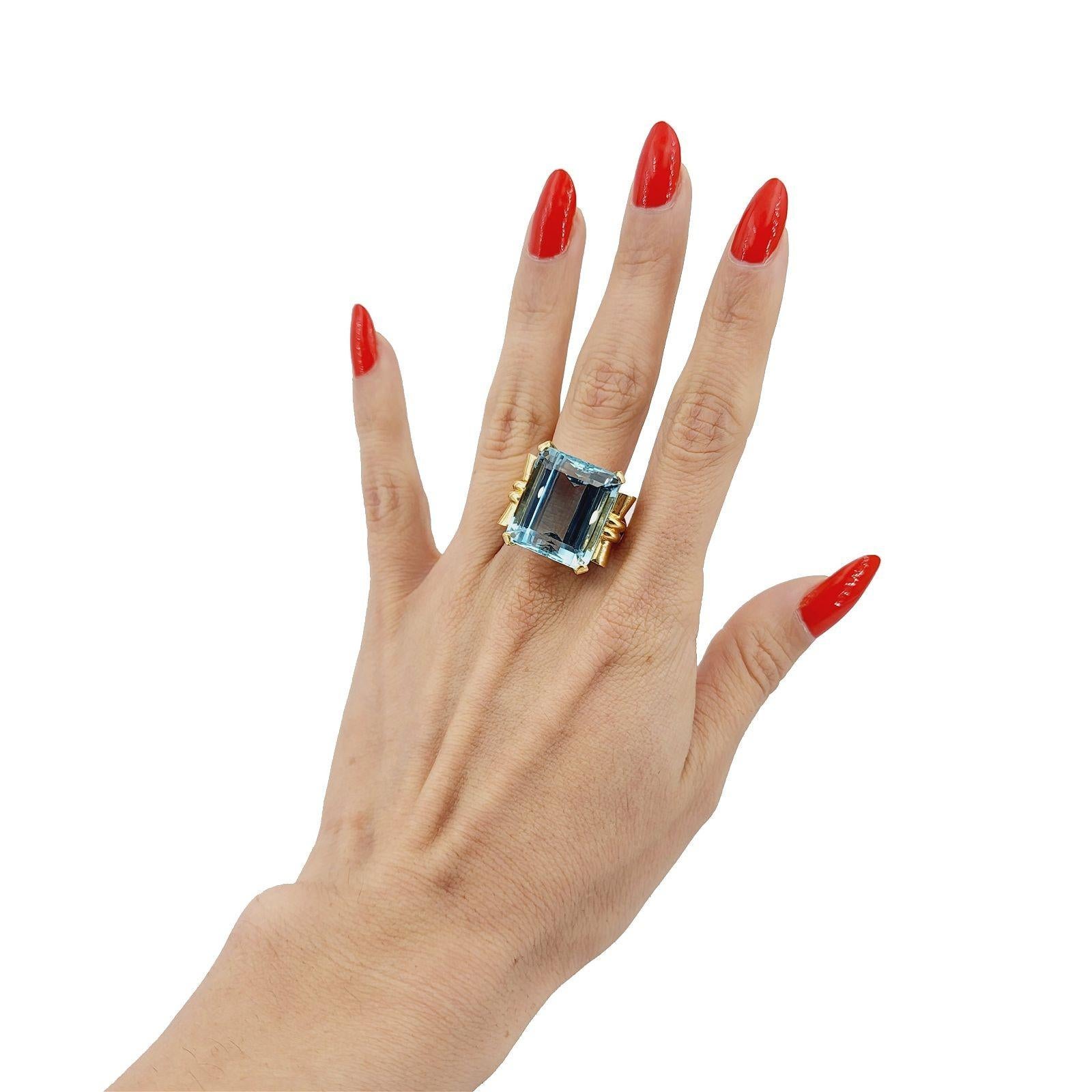 Retro 18k yellow Gold Ring featuring a center Emerald cut Brazilian Aquamarine weighing Approximately 25.2 Carats. 

A retro 18k yellow gold ring with a center Emerald cut aquamarine sounds absolutely stunning! Aquamarine is known for its serene