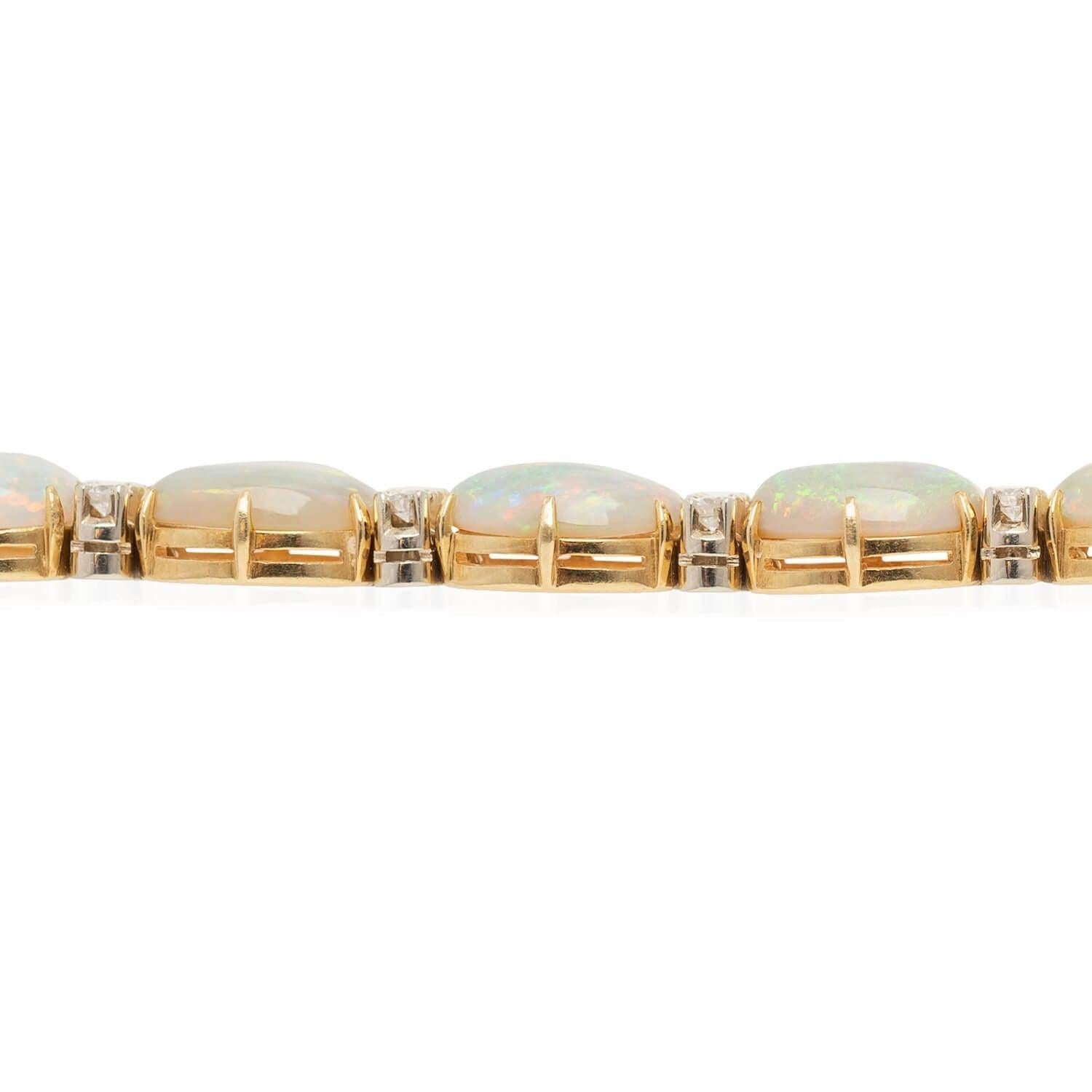 A gorgeous opal and diamond bracelet from the Retro (ca1940s) era! Crafted in 18kt yellow gold and platinum, twelve fiery white opals emit incredible rainbow hues! Each held atop their yellow gold frame by six prongs, the gorgeous opals display