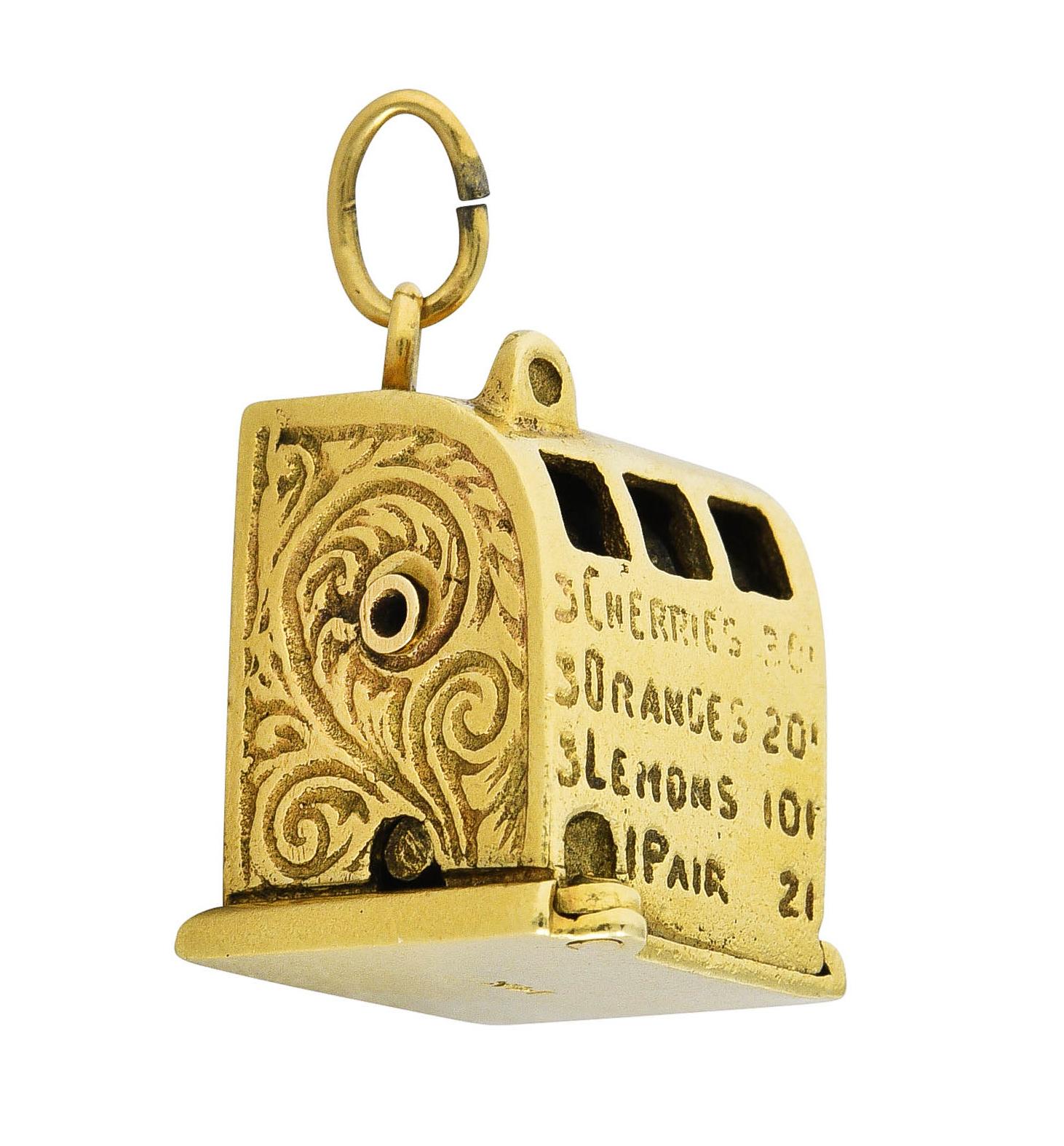 Charm is designed as a highly rendered antique style gold slot machine. Featuring a functional lever with rotating icons viewable through pierced slots. Depicting different fruits with yellow enamel - loss consistent with age. Decoratively engraved
