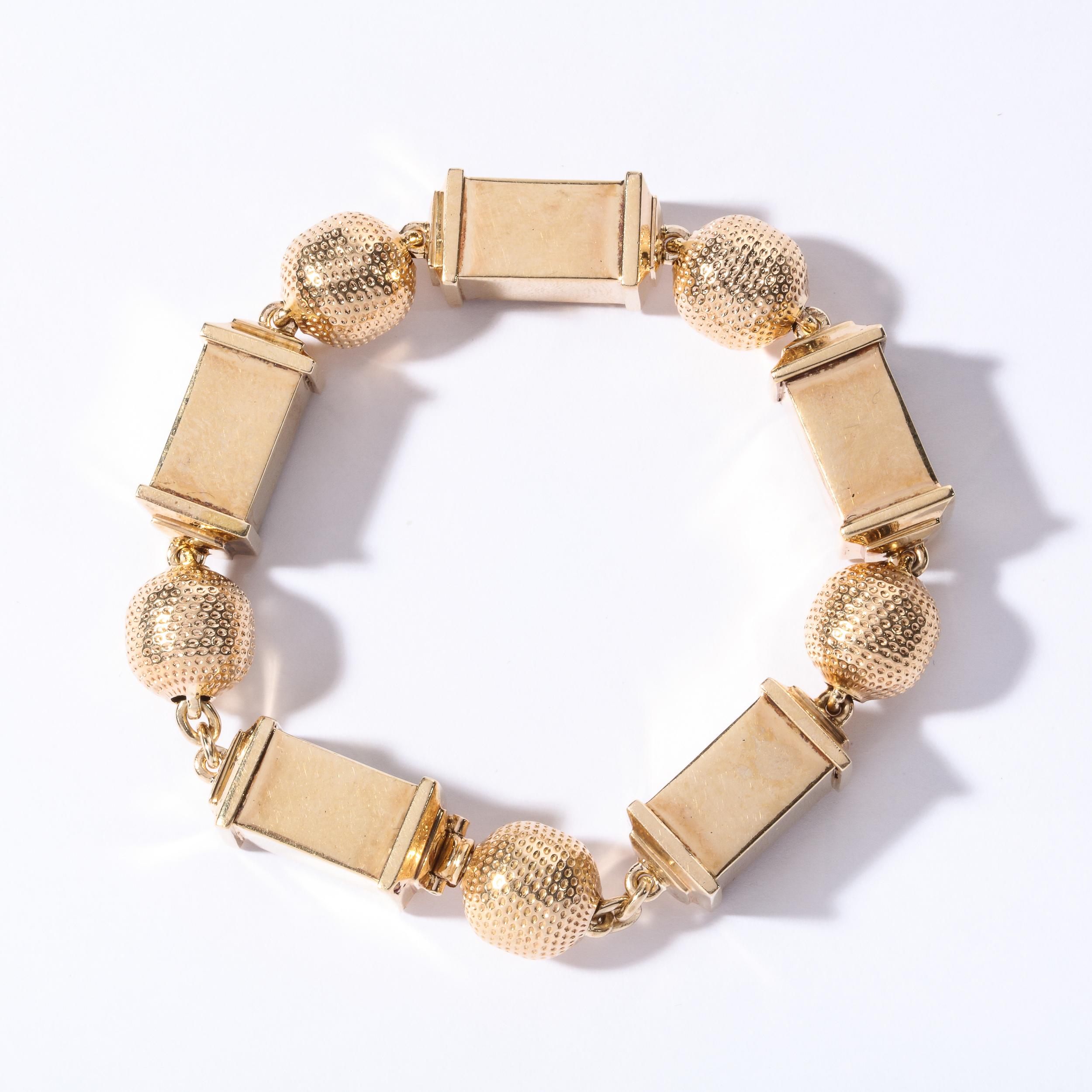 This stunning retro ruby, diamond and rose gold bracelet was realized in the United States, circa 1940. It offers contrasting geometric forms with an alternating ball and cylinder design. The ball has a dimple pattern design with alternating