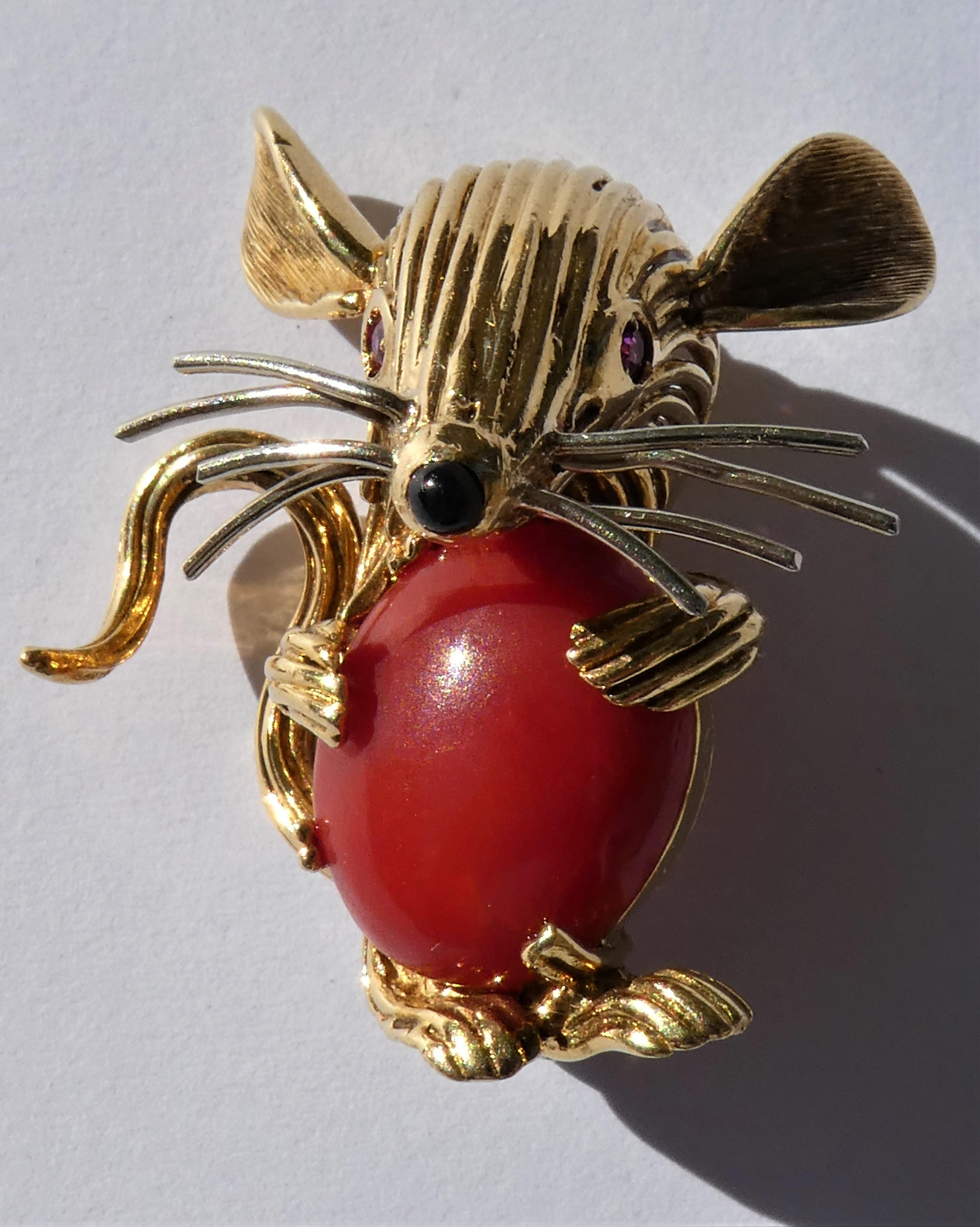 This lovely mouse brooch was crafted in Italy in the 1950s in 18 karat yellow gold. It has wonderful details like a chubby belly made out of a dark red Mediterranean coral cabochon and a black onyx nose. The mouse has 2 round cut vibrant red ruby