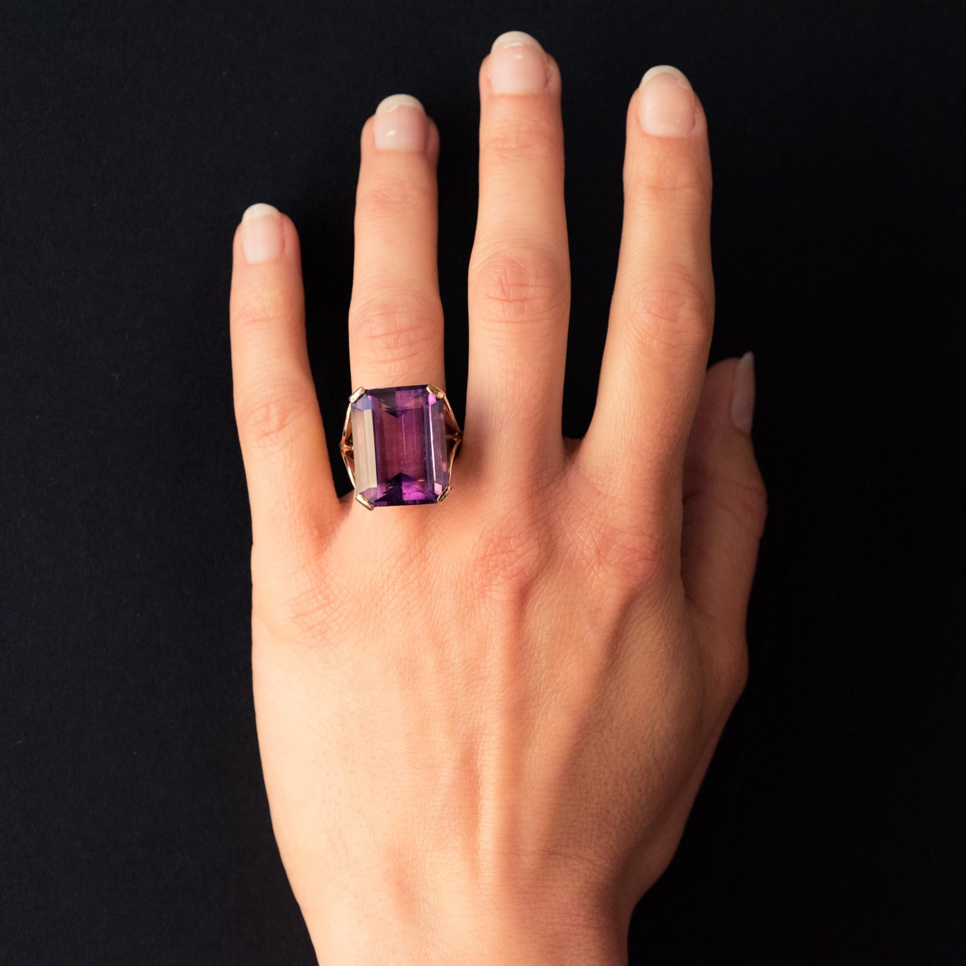 Ring in 18 karat yellow gold.
Important retro ring, its setting is formed by 2 x 2 large gold palmettes extended by 4 flat claws which hold an emerald-cut amethyst. The setting and the basket are perforated to let the light come under the gem and