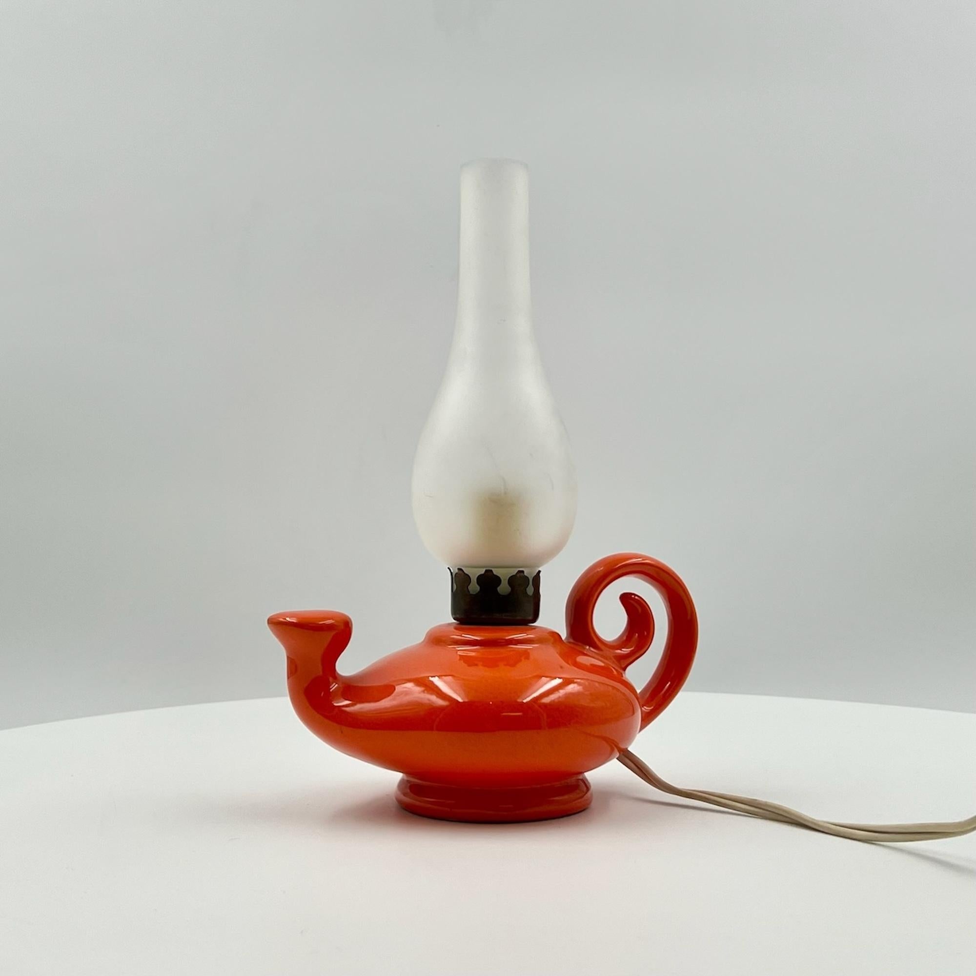 Elevate your decor with this charming 60s lamp, reminiscent of Aladdin’s magic lamp, made in Italy in the 1960s. This beautiful mid-century light boasts a shining ceramic base with an eye-catching orange hue, a signature color of the era. The golden
