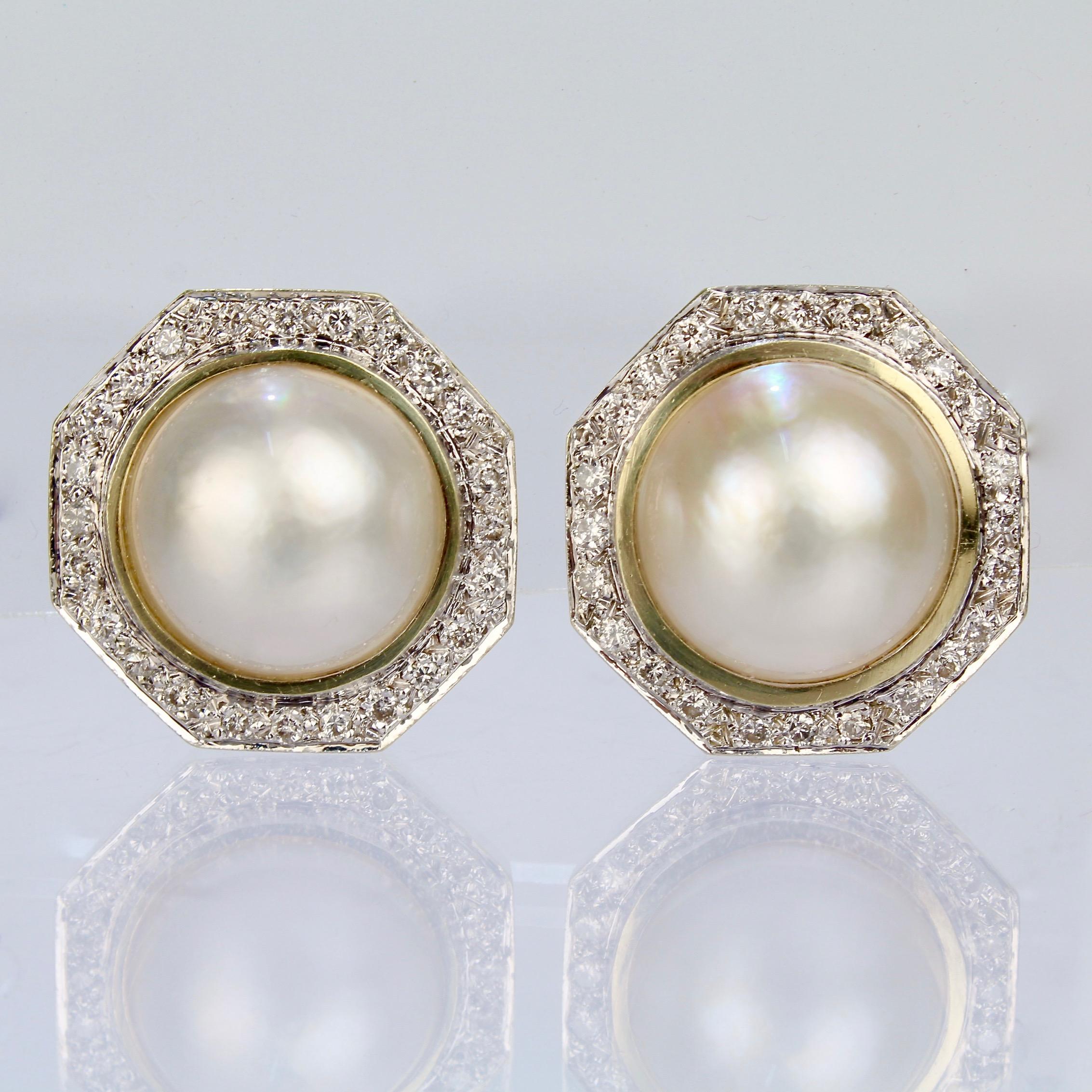 A fine pair of 14K gold, diamond and mabe pearl earrings.

With large mabe pearls center-set in hexagonal settings that are surrounded by a ring of round cut white diamonds.

Mounted with omega clip closures.

Unmarked for gold fineness.