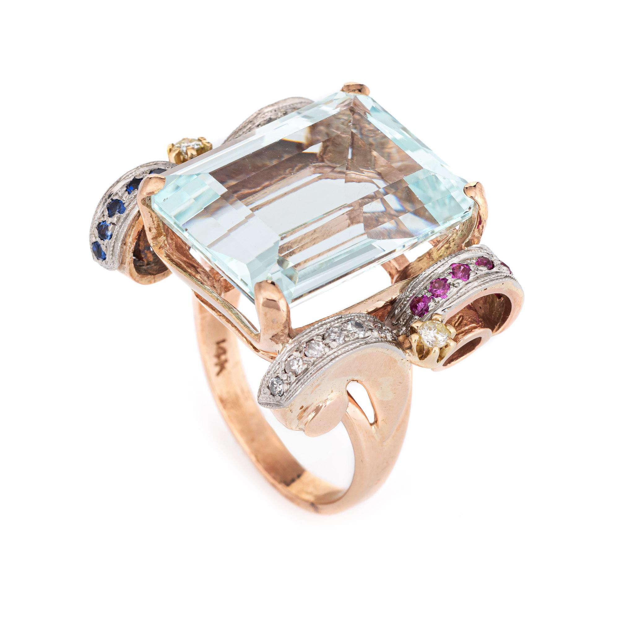 Stylish vintage aquamarine, diamond, sapphire & ruby ring (circa 1940s to 1950s) crafted in 14 karat rose gold. 

Emerald cut aquamarine measures 20mm x 15mm (estimated at 22 carats), accented with 0.15 carats of diamonds. The diamonds are estimated