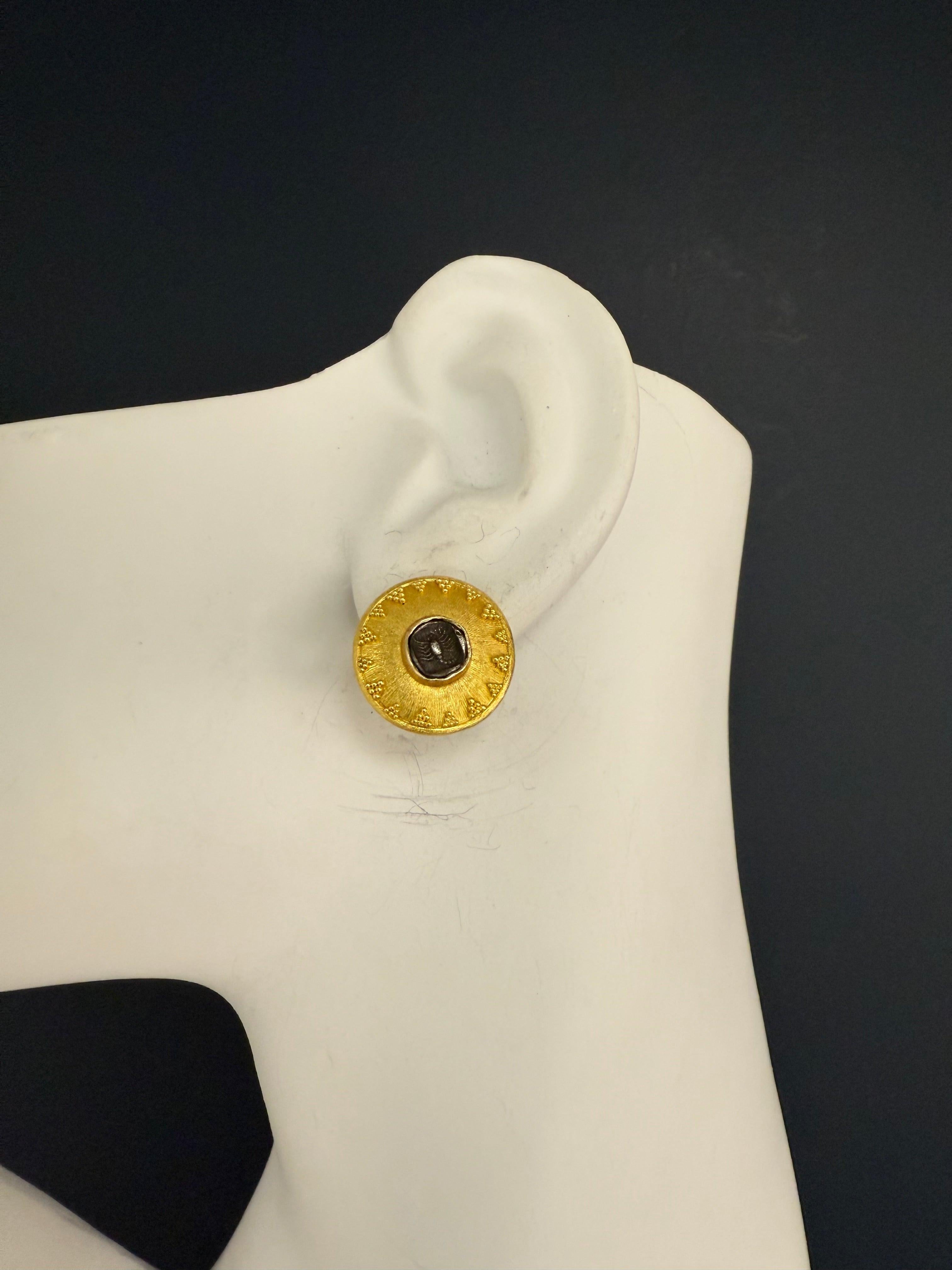 Un caratteristico paio di orecchini in oro retrò firmati IRA, realizzati nel 1997, con motivi di monete dello zodiaco dello scorpione. Le piastre principali sono in oro 22 carati con una finitura opaca e perlinata, con il simbolo dello scorpione che