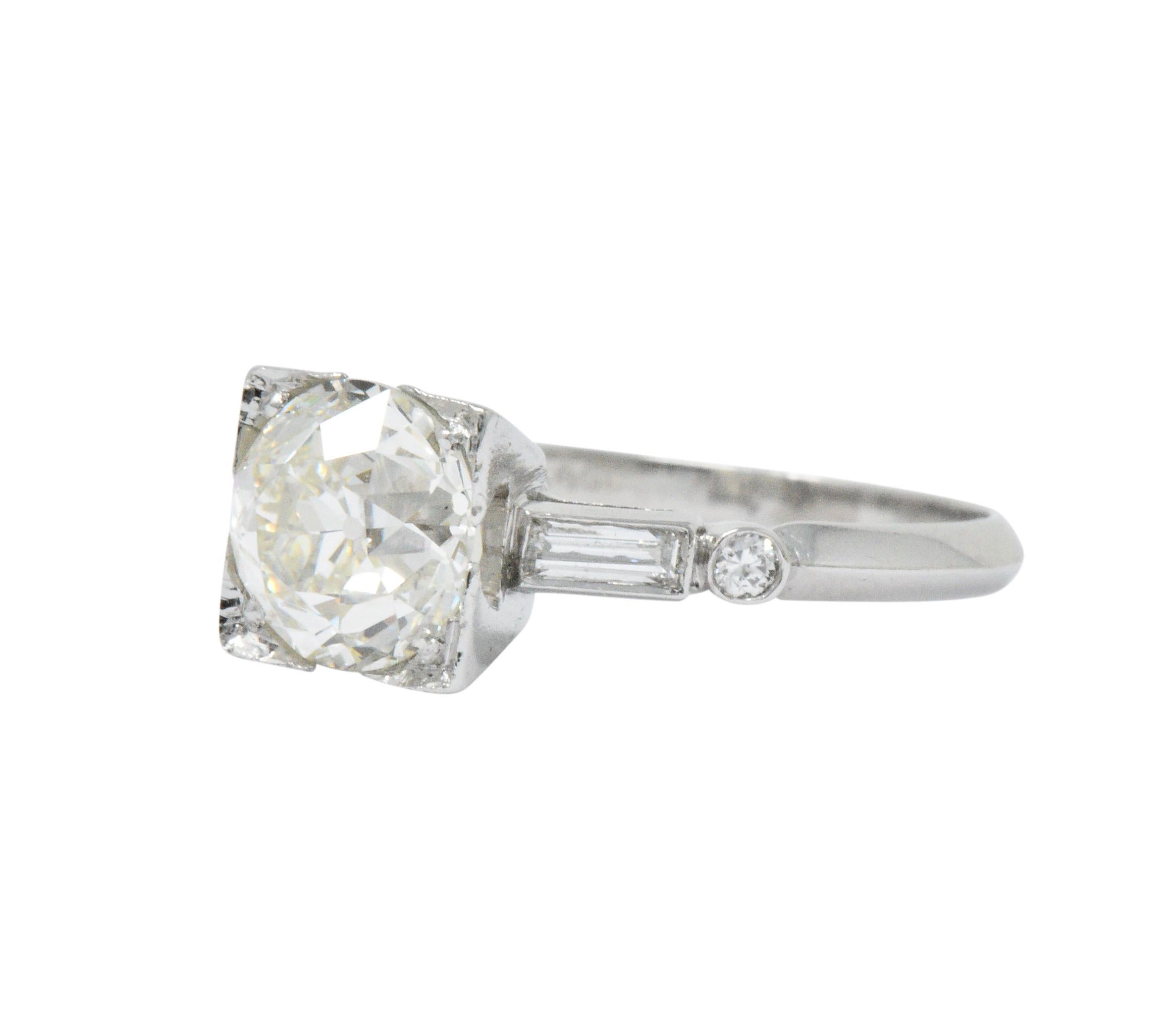 Centering an old European cut diamond weighing 1.94 carats, L color with VS1 clarity

Set in a decoratively pierced square form head then flanked by straight baguette cut diamonds and single cut diamonds; flush set in cathedral style