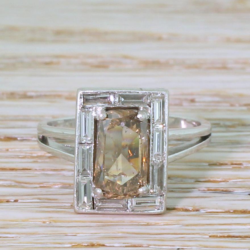 An impressively eye-catching Retro diamond ring. This wonderful statement piece features a rectangular cushion shaped diamond in the centre which displays a lovely, warm fancy orangey brown. The centre stone sits within a surround of ten baguette