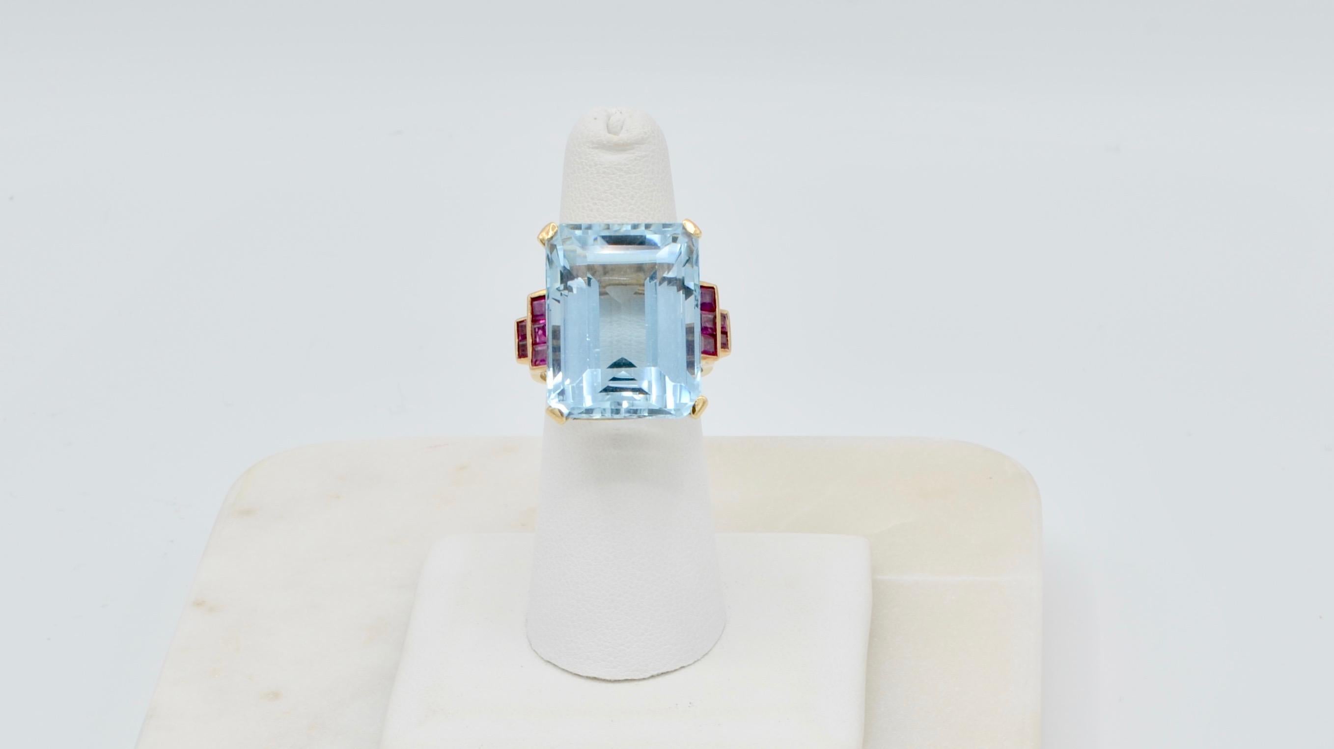 This beautiful rectangle step cut aquamarine is a medium tone and transparent weighing in at 31 carats. The setting is 14 karat yellow gold size 6 with two beads inside the band to balance the weight. It has ten channel set square step cut natural