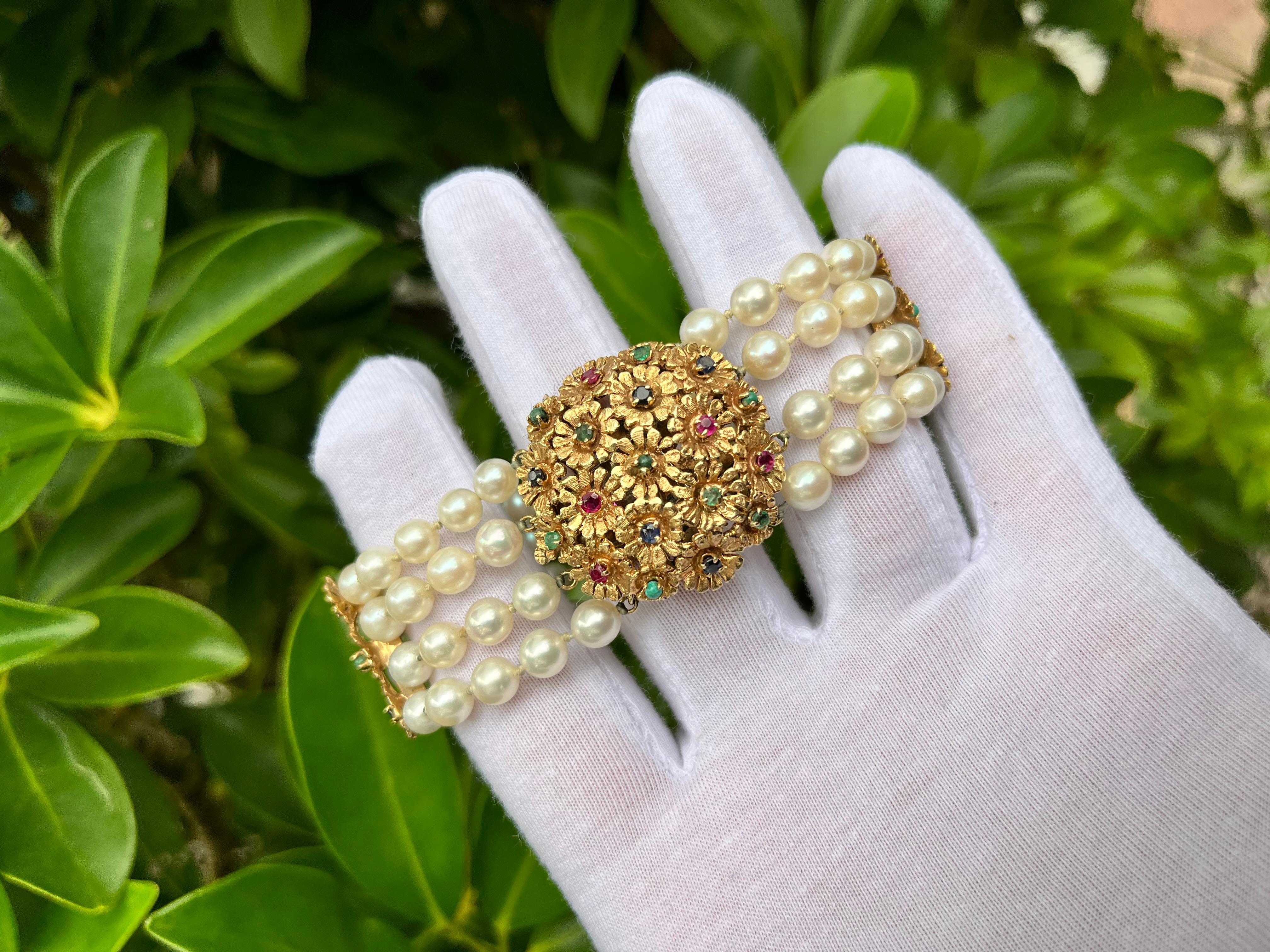 14K yellow gold pearl and multi-gemstone (Emerald, Ruby and Sapphire) Bracelet. Floral design and retro style. Mounted in a 4-prong setting with 28 round-cut gemstones. 

✔ Metal: Gold 
✔ Metal Purity: 18K 
✔ Length: 7 inches 
✔ Width: 0.80 inches