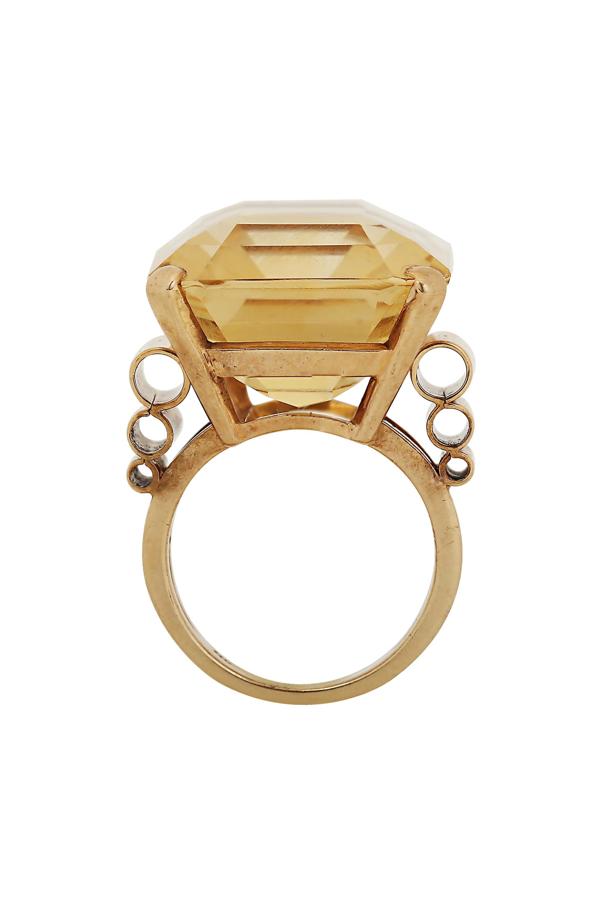 A boldly scaled Retro ring featuring a magnificent citrine of approximately 40 carats highlighted at either side by a tailored trio of graduating scrolls of gold. Currently size 6.5. This ring may be resized.
