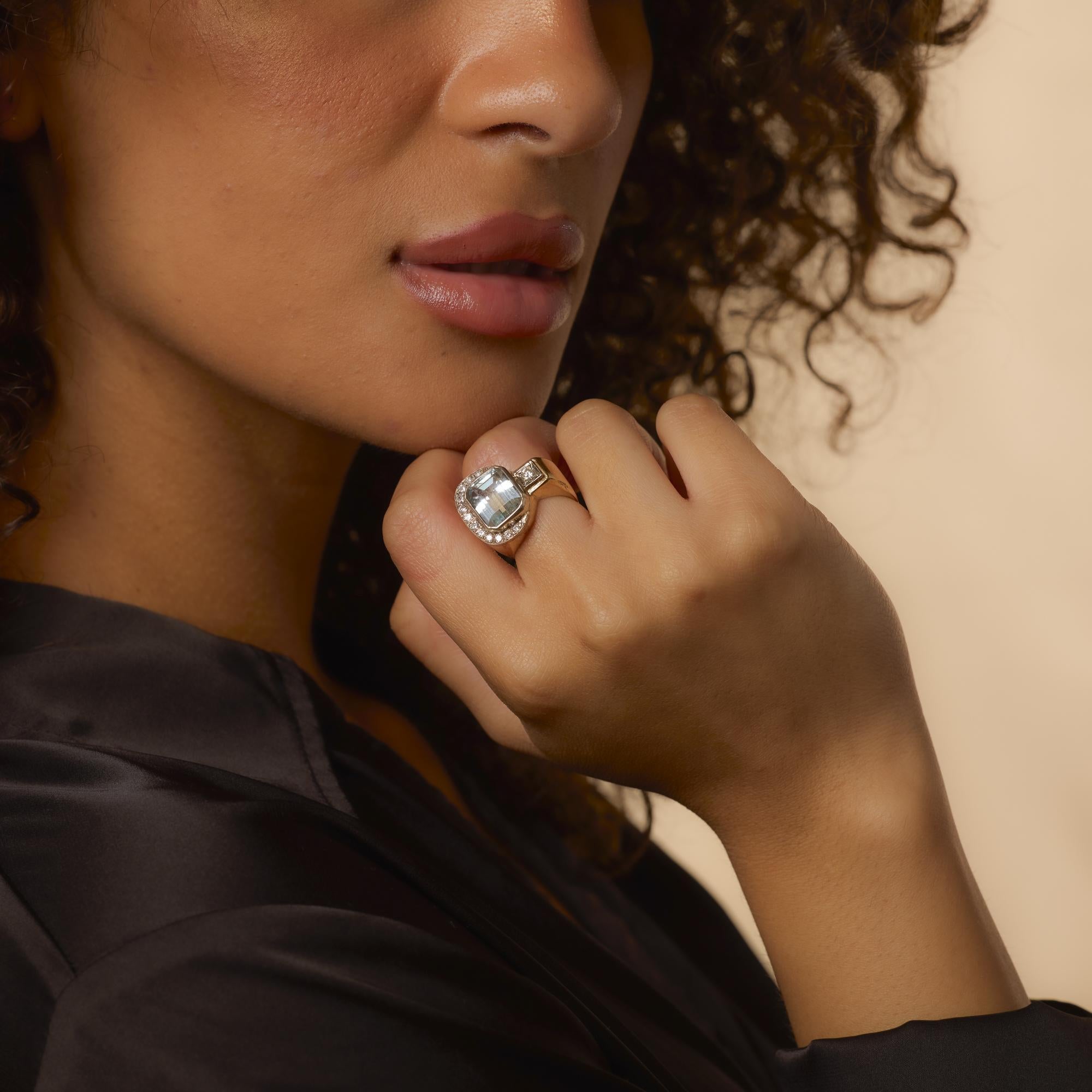 This Retro 14k yellow gold ring showcases a bold emerald cut aquamarine flanked by shimmering F-G color diamonds in a timeless and graceful silhouette.