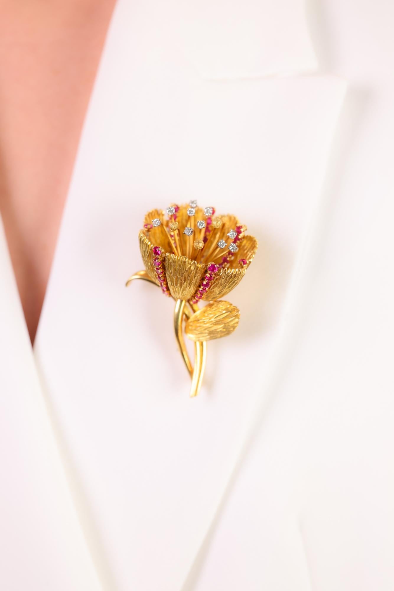 Questa spilla a fiore di tulipano retrò degli anni '40 sfoggia 5 carati di vibranti rubini e 0,50 carati di splendidi diamanti, elegantemente realizzati in oro giallo e bianco 18 carati.

Pietra centrale: 40 rubini rotondi taglio brillante
Peso