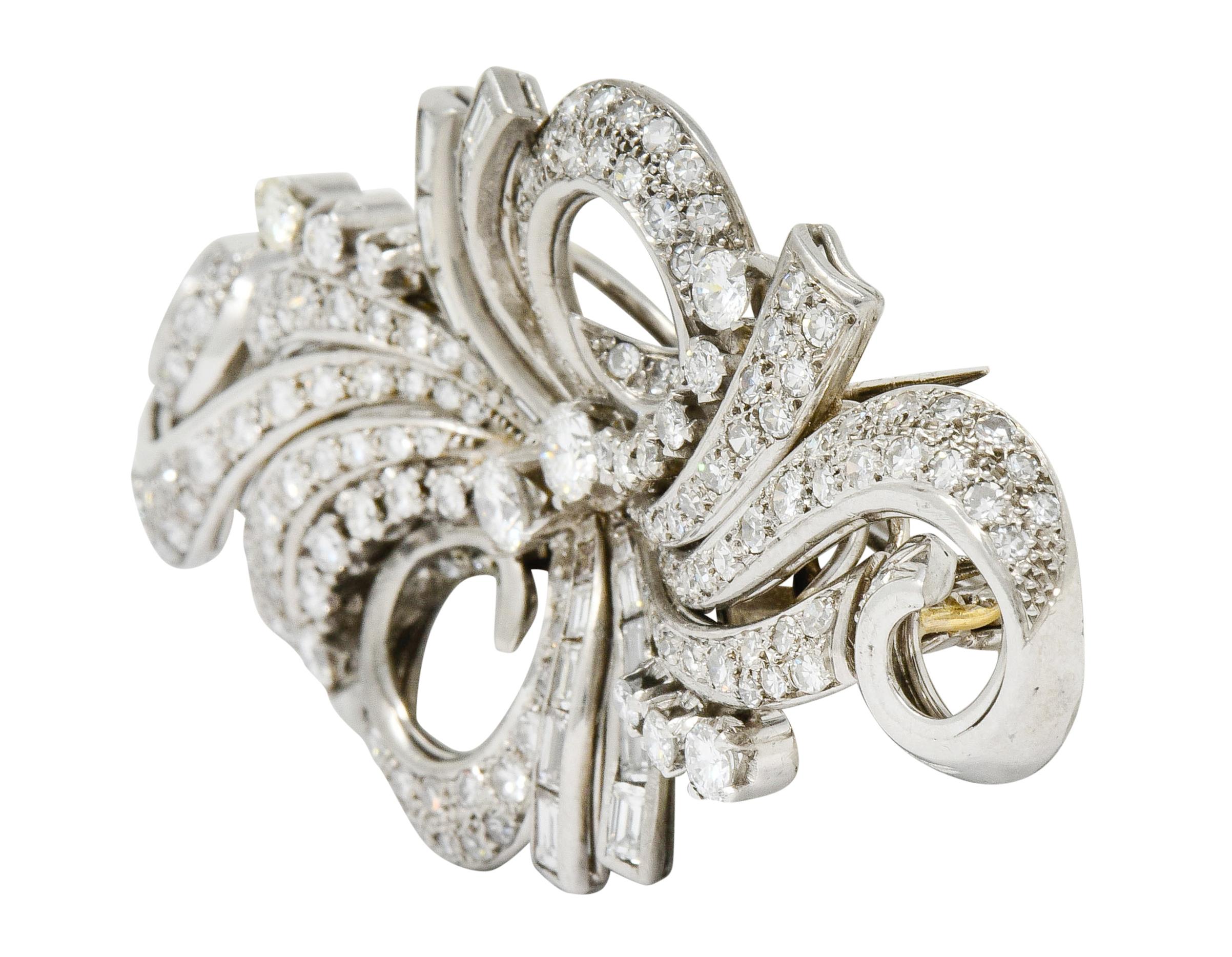 Brooch is comprised of two symmetrical scrolling ribbon motifs that can convert into two individual clips

Designed as winding ribbon-like segments that center two round brilliant cut diamonds that weigh in total 0.50 carat, J/K color with SI