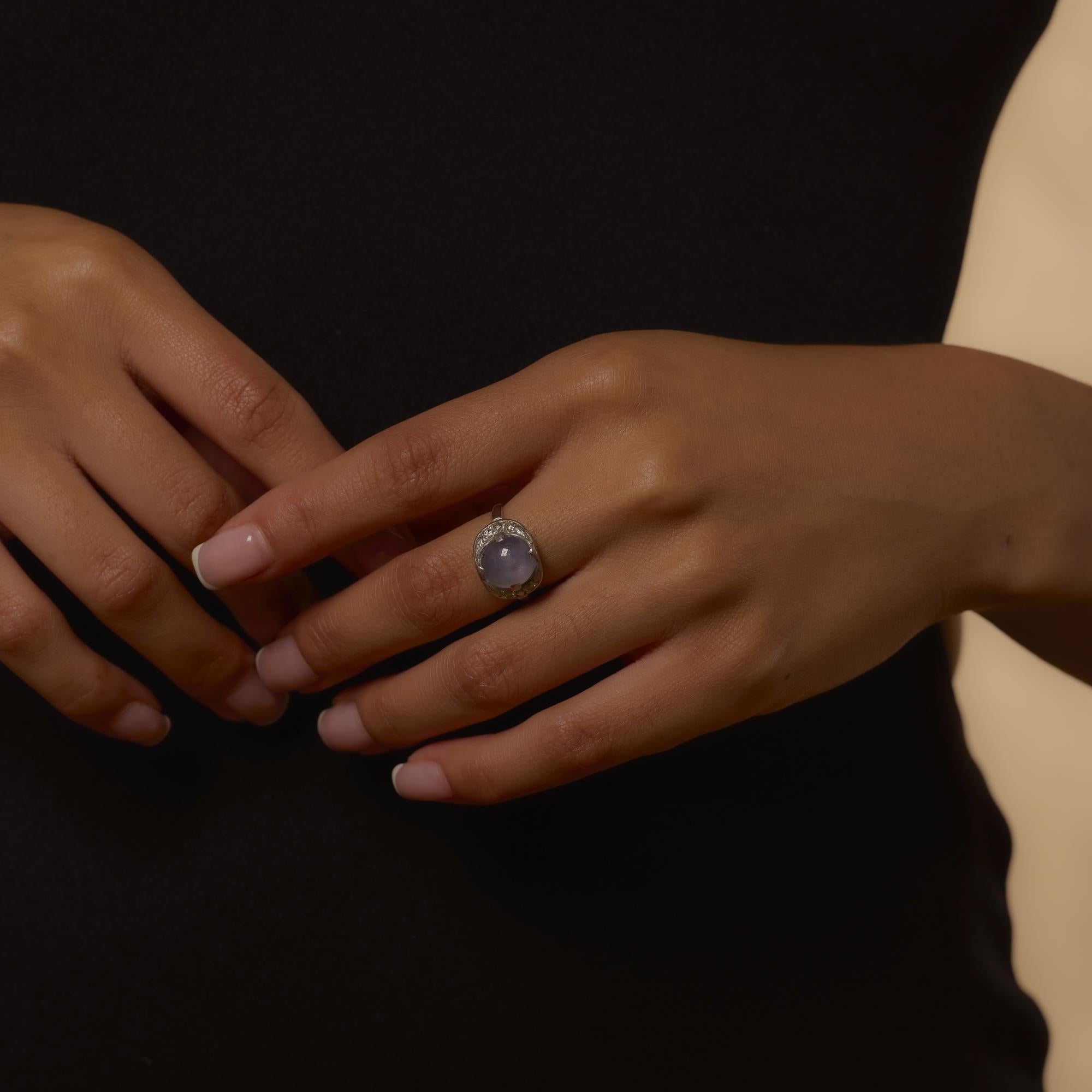 This Retro-era ring from the 1940s features a glowing 5.80 carat cabochon cut star sapphire, showcasing a soft, shimmering asterism under light. Framed by four round brilliant cut diamonds totaling approximately 0.10 carats, the ring balances
