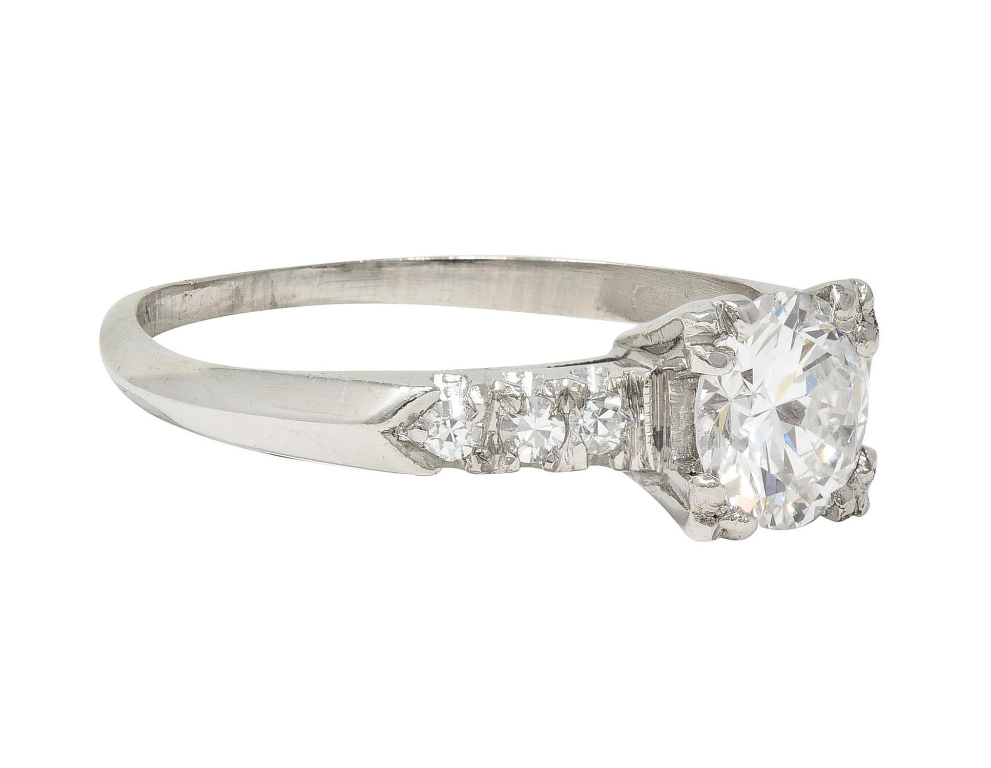 Centering a transitional cut diamond weighing approximately 0.60 carat - J color with SI1 clarity
Set with tri-split prongs in a square form basket - pierced with 'V' motif profile 
Flanked by single cut diamonds prong set in cathedral shoulders
