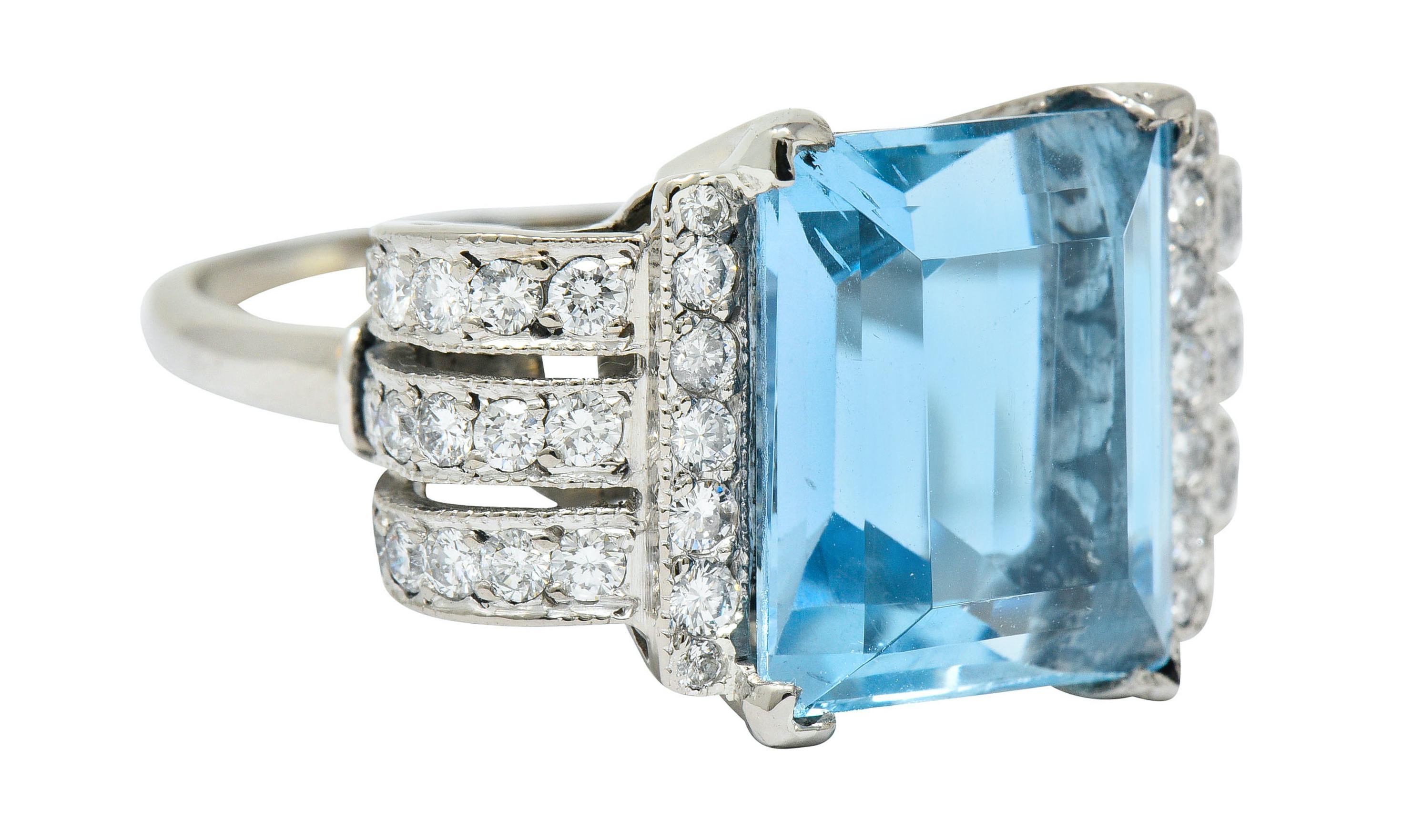 Magnificent mounting designed with scrolled shoulders decorated with a pierced design

Centering a basket set rectangular step cut aquamarine weighing approximately 6.70 carats; bright greenish-blue in color

Flanked by rows of round brilliant cut