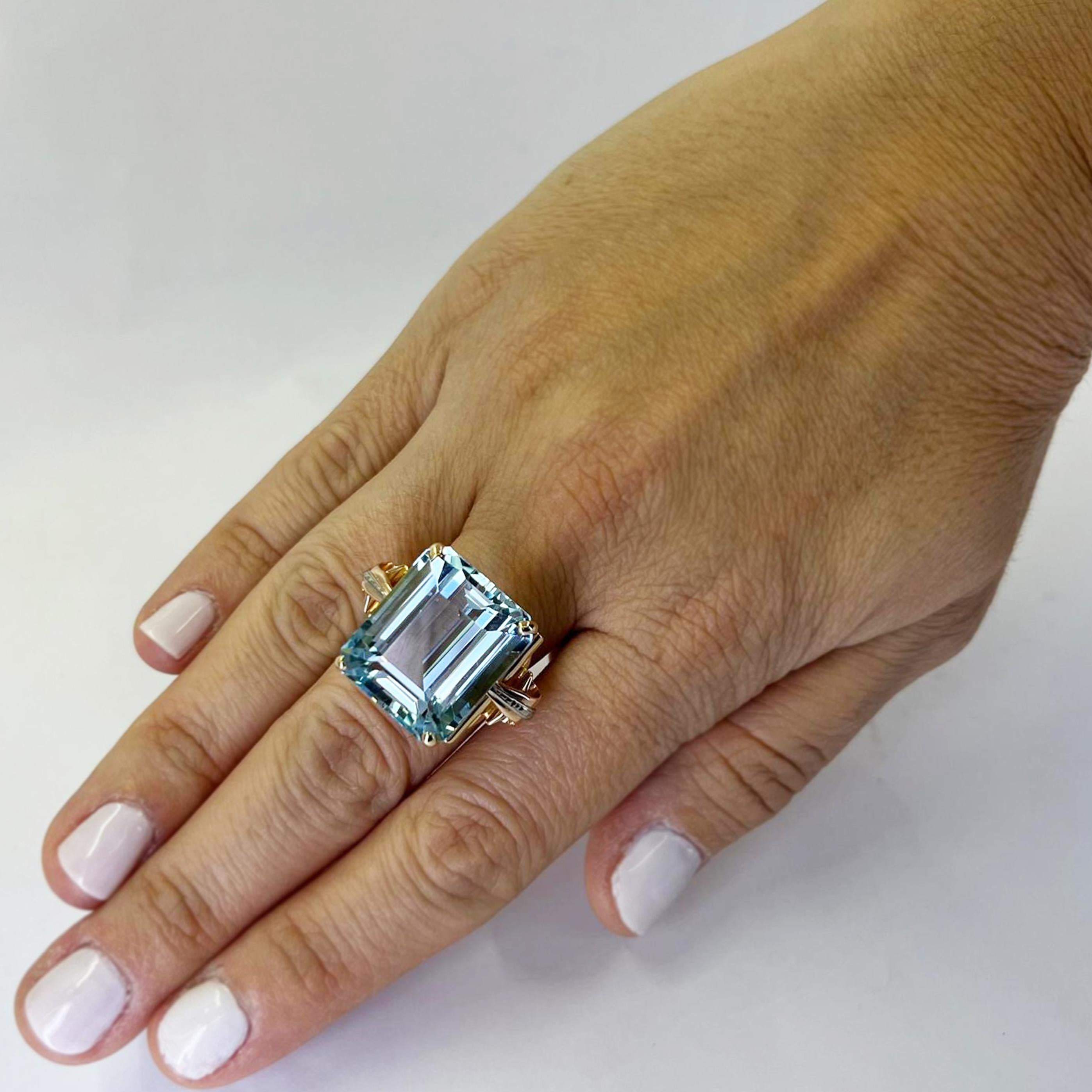 18 Karat Yellow Gold Retro Ring Featuring an Emerald Cut Aquamarine Estimated to Weight 26 Carats Accented by White and Rose Gold Scrolls. Finger Size 6.25. Includes One Sizing Service Prior to Shipping, Upon Request. Finished Weight is 14.0 Grams.