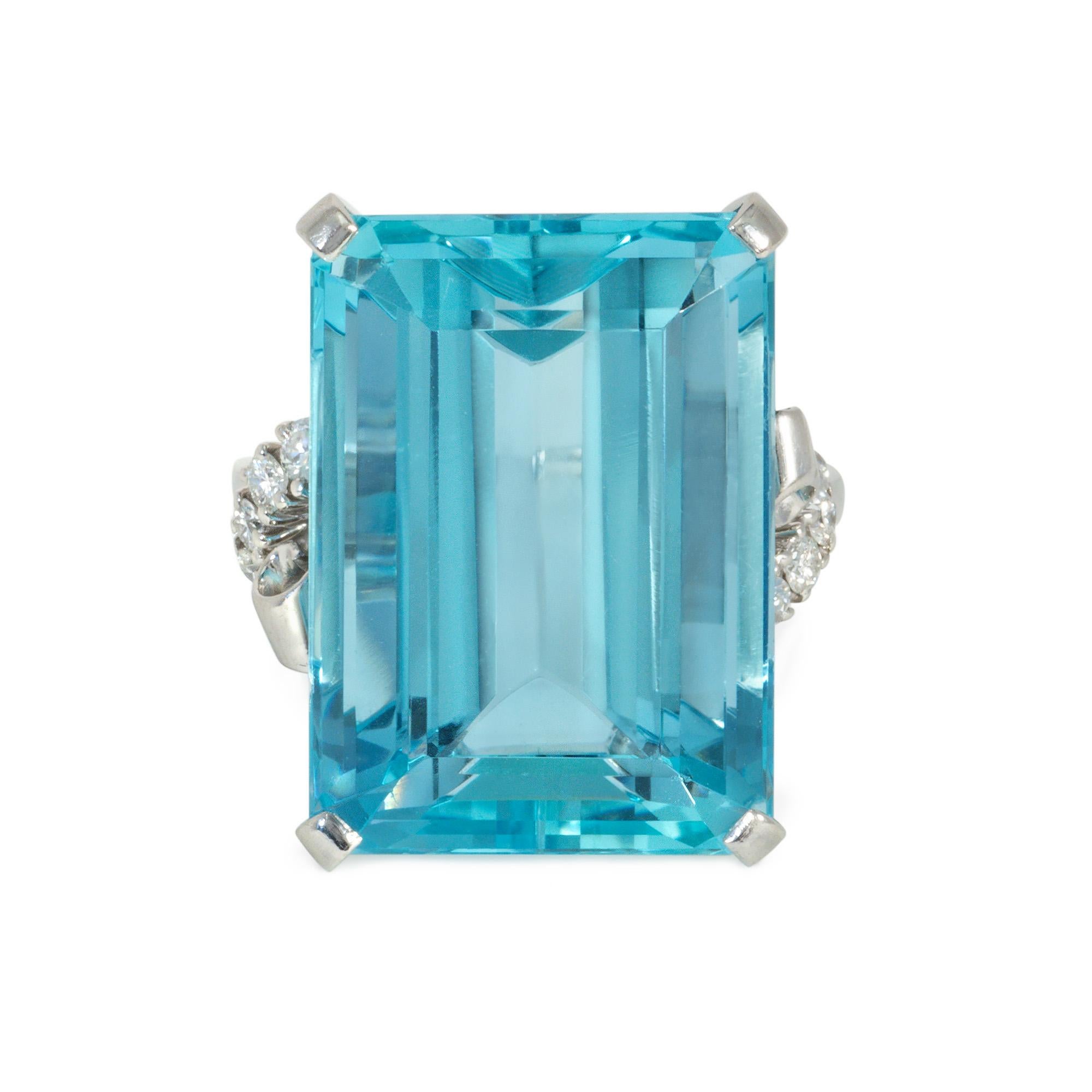 A Retro aquamarine and diamond cocktail ring centered by a step-cut aquamarine and flanked by scrolling, diamond-set shoulders, in platinum.  Atw aquamarine 23.61 cts. (face: 15mm wide, 21mm long), atw diamonds 0.25 ct.

* Includes letter of