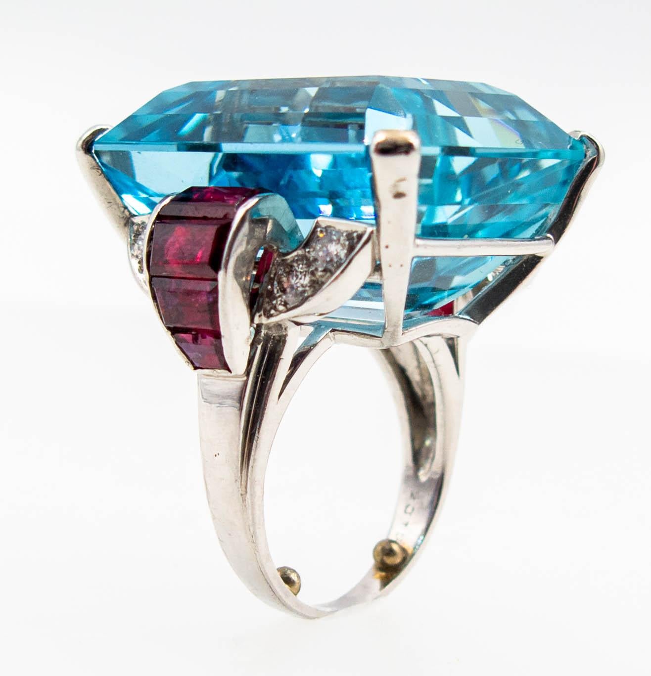 This exceptionally chic ring was probably made in the late 1930's, and features a large emerald cut aqua weighing about 43 carats, flanked at the shoulders with petite diamonds (about .40 total) and large baguette rubies.  The aqua spreads an inch