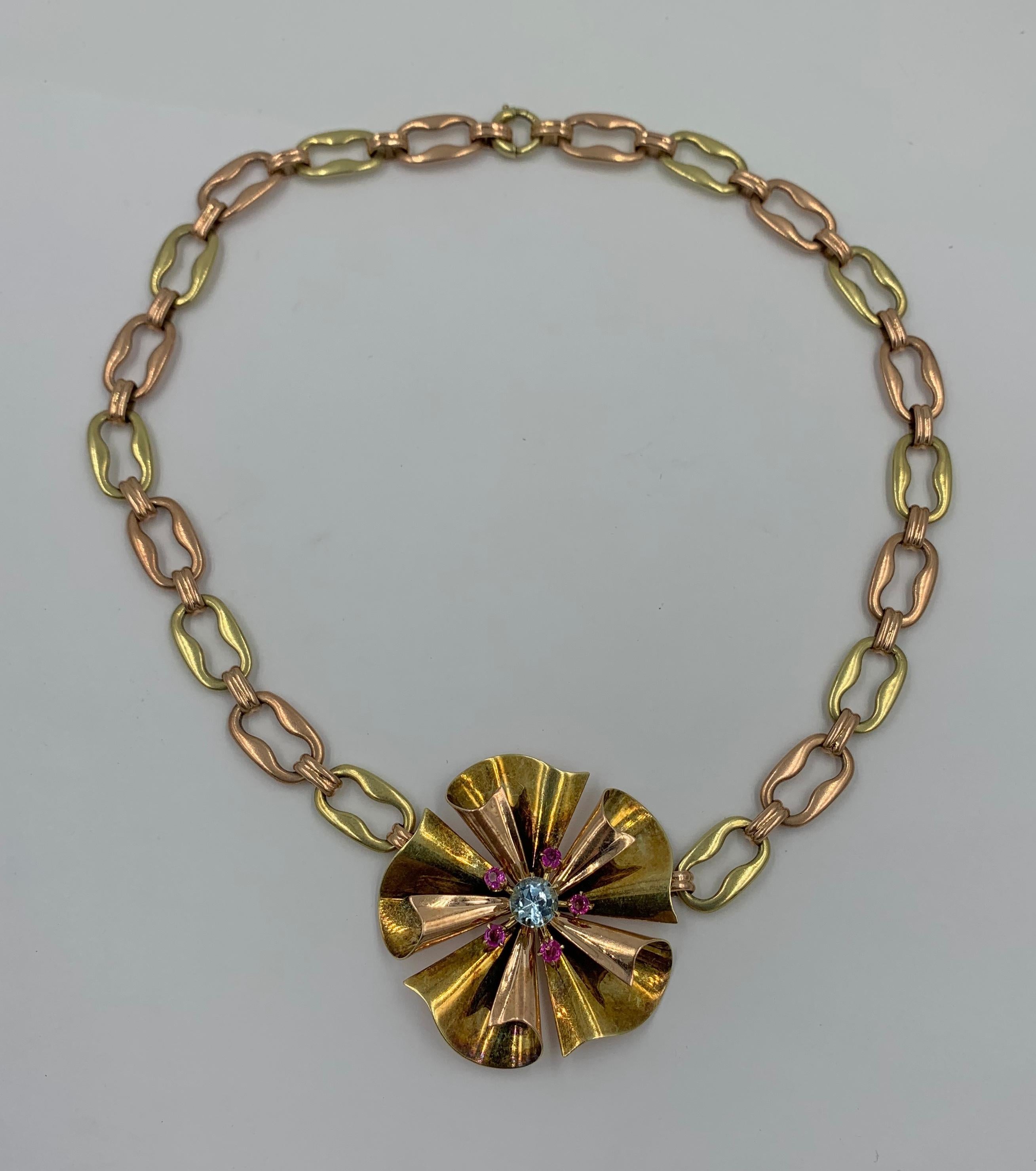 This is a stunning Retro Mid-Century stylized flower motif necklace set with a central 1 Carat Aquamarine and five round Rubies set in 14 Karat Pink Gold with a Yellow Gold Mariner Link Chain.  The fabulous Mid-Century necklace has wonderful Retro