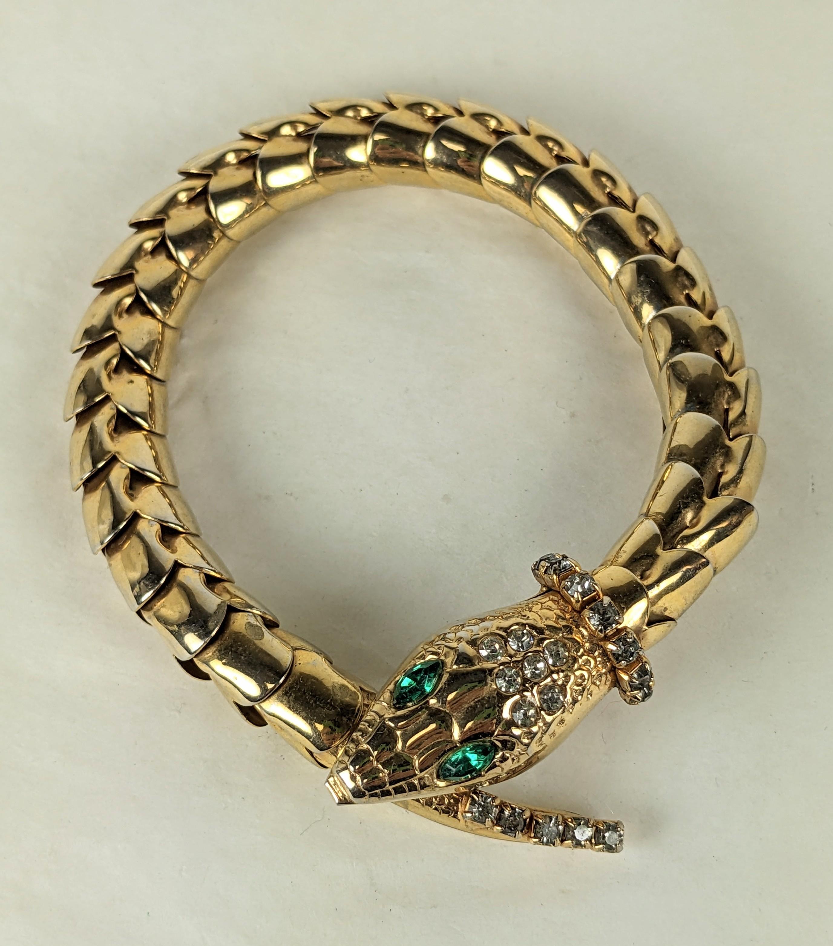 Retro Articulated Snake Bracelet from the 1940's of gilt metal with paste accents and emerald paste eyes. Scalloped links form the body of the snake. Button lock under head and tail. 9.5