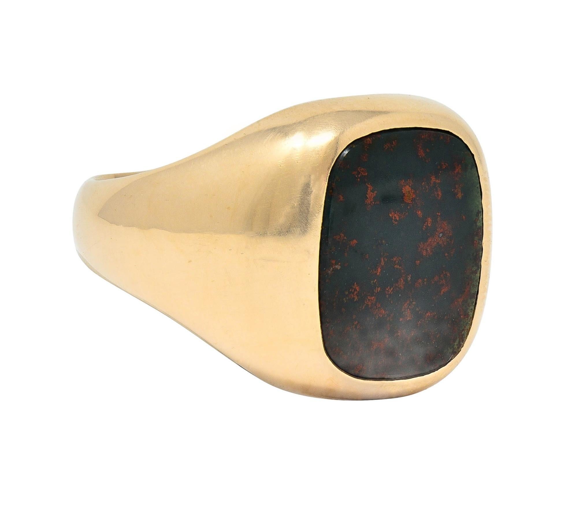 Centering a cushion-shaped bloodstone tablet measuring approximately 14.0 x 12.2 mm
Semi-opaque and dark bluish-green in color accented by bright red mottling
Flush set with a slight bombé shaped surround
Stamped 14K for 14 karat gold
With maker's