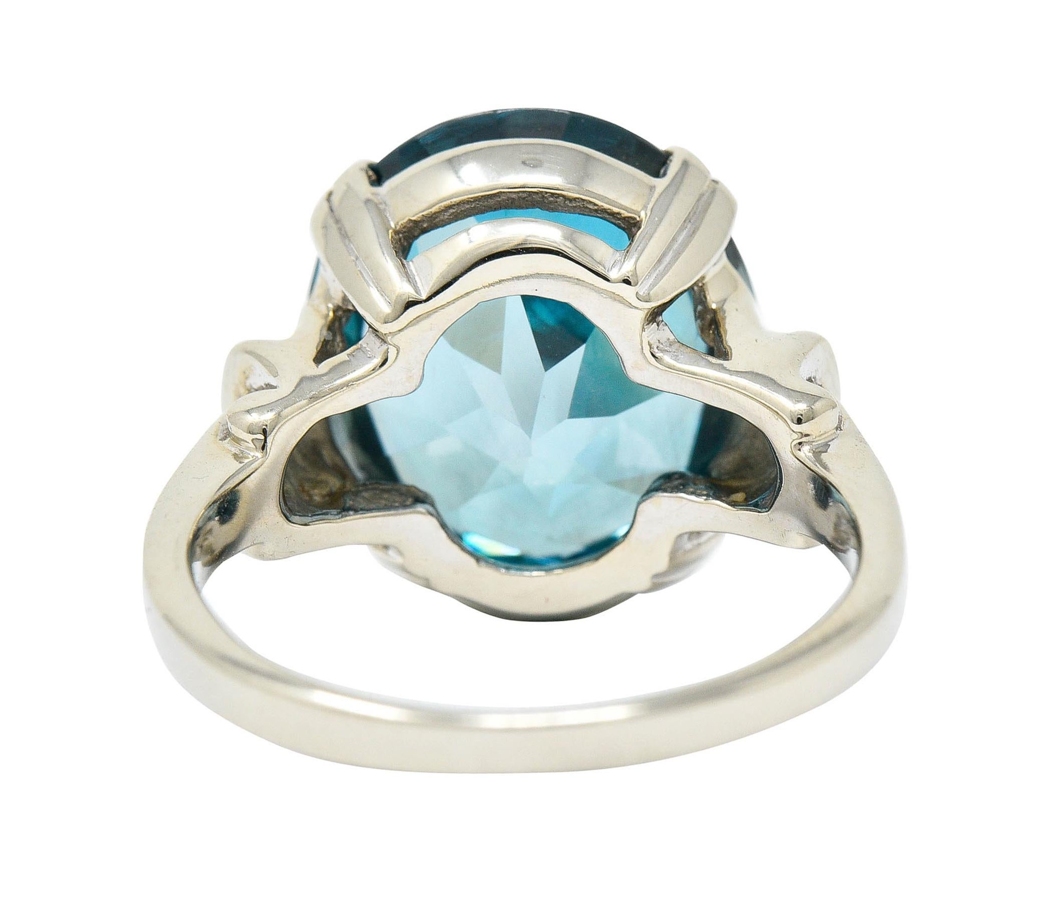 Centering an oval cut zircon measuring approximately 14.0 x 11.8 mm

Transparent with strong greenish blue color

Basket set by wide split prongs and flanked by stylized shoulders

Stamped 14K for 14 karat gold

Circa: 1940s

Ring Size: 5 3/4 &