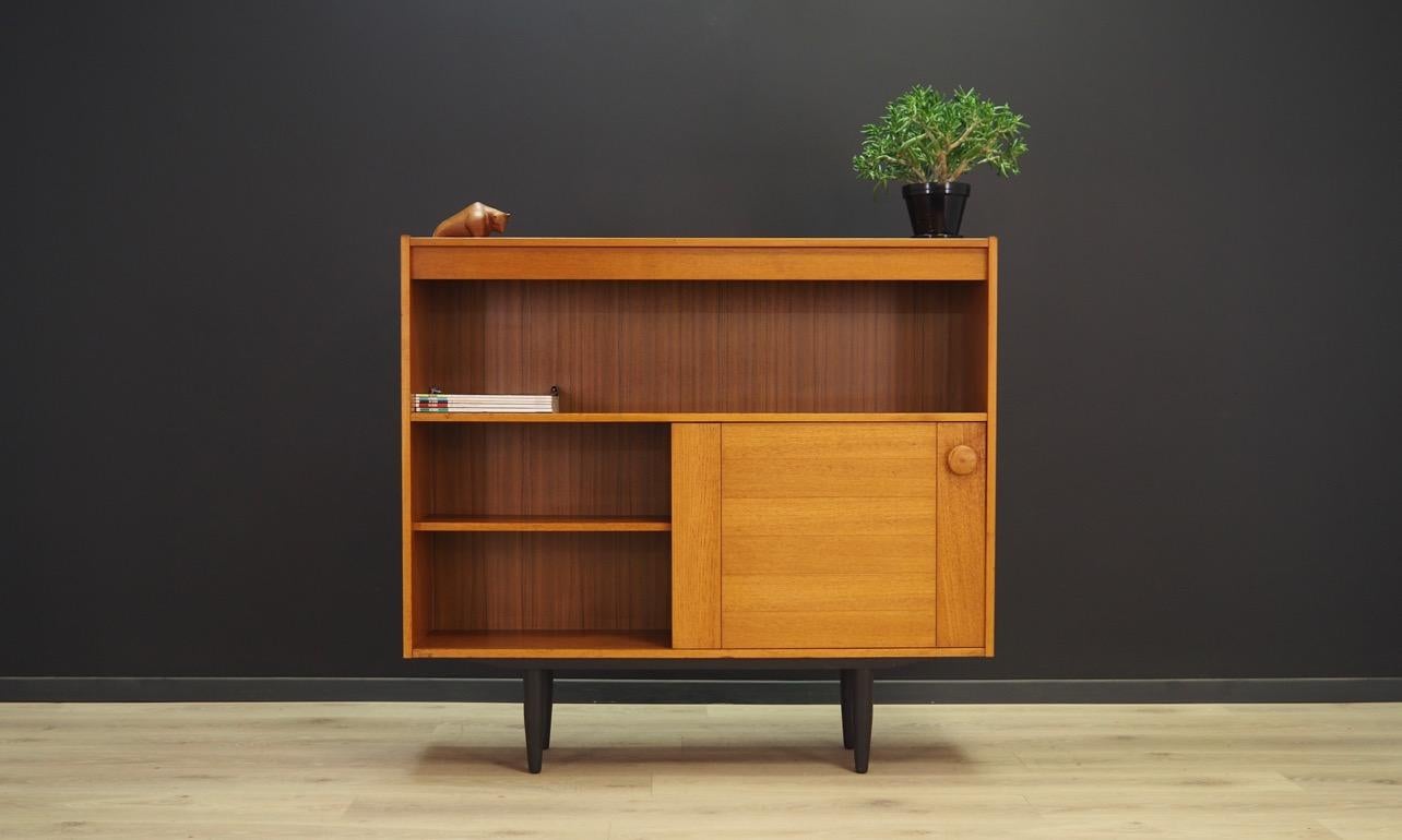 Extraordinary bookshelf from the 1960-1970. Minimalistic form, Danish design. Bookshelve veneered with teak. A shelve behind sliding doors. Preserved in good condition (minor bruises and scratches) - directly for use.

Dimensions: Height 110 cm,