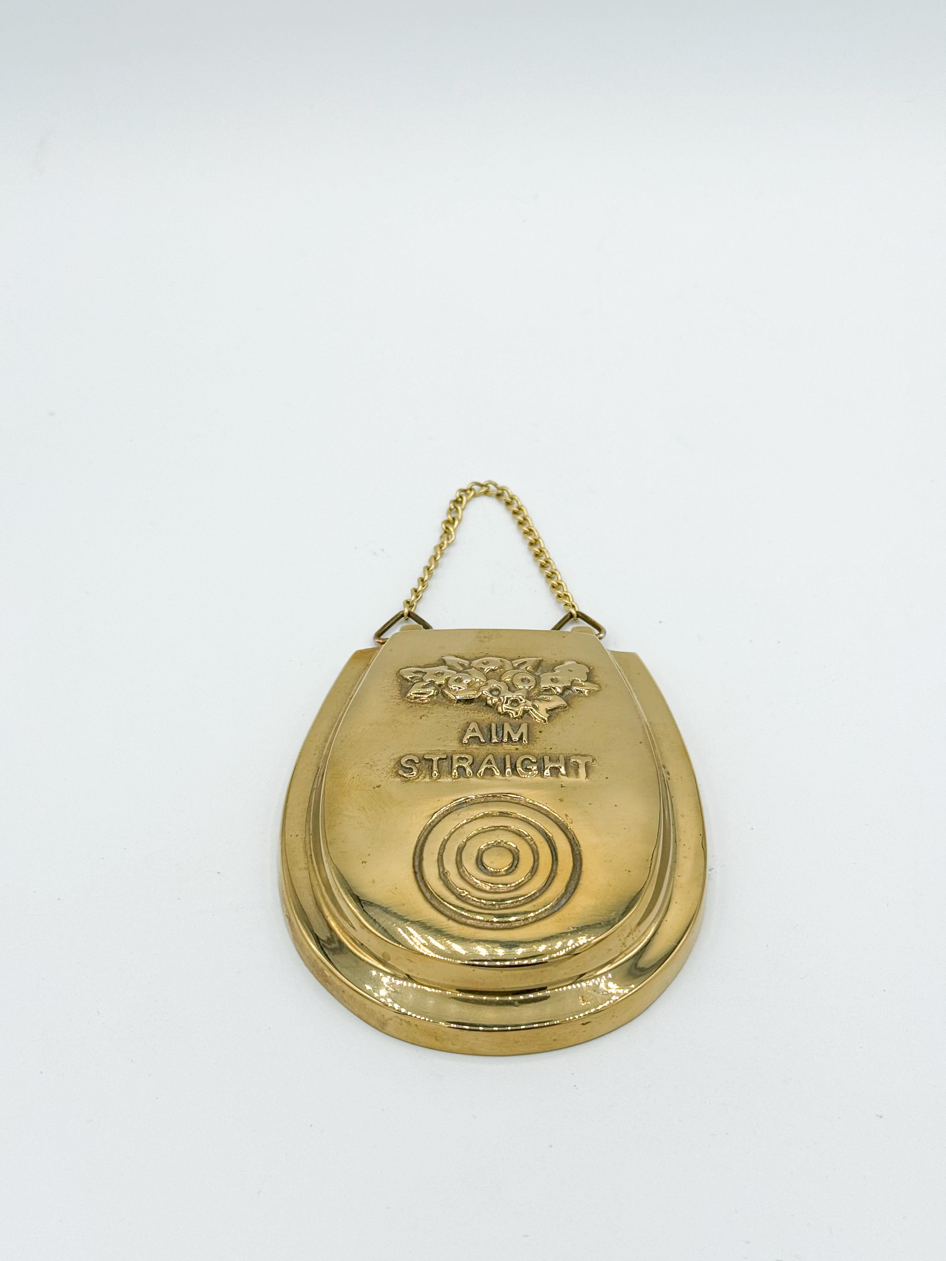 Bring humor into your home with this vintage brass wall hanging from the 1970s, shaped like a toilet seat and emblazoned with the cheeky reminder to 