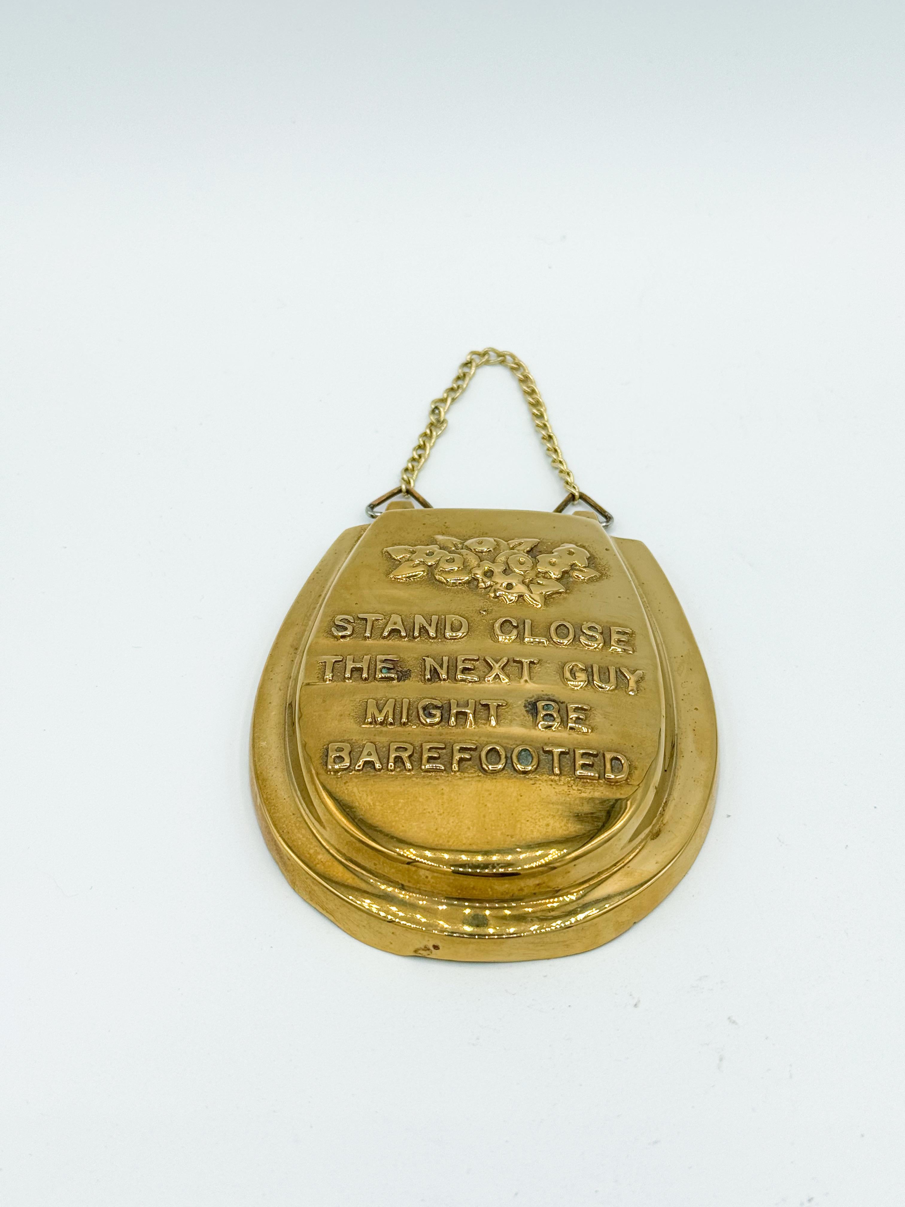 This fun and quirky vintage brass wall hanging is a playful addition to any room, especially bathrooms. Shaped like a mini toilet seat, it reads 